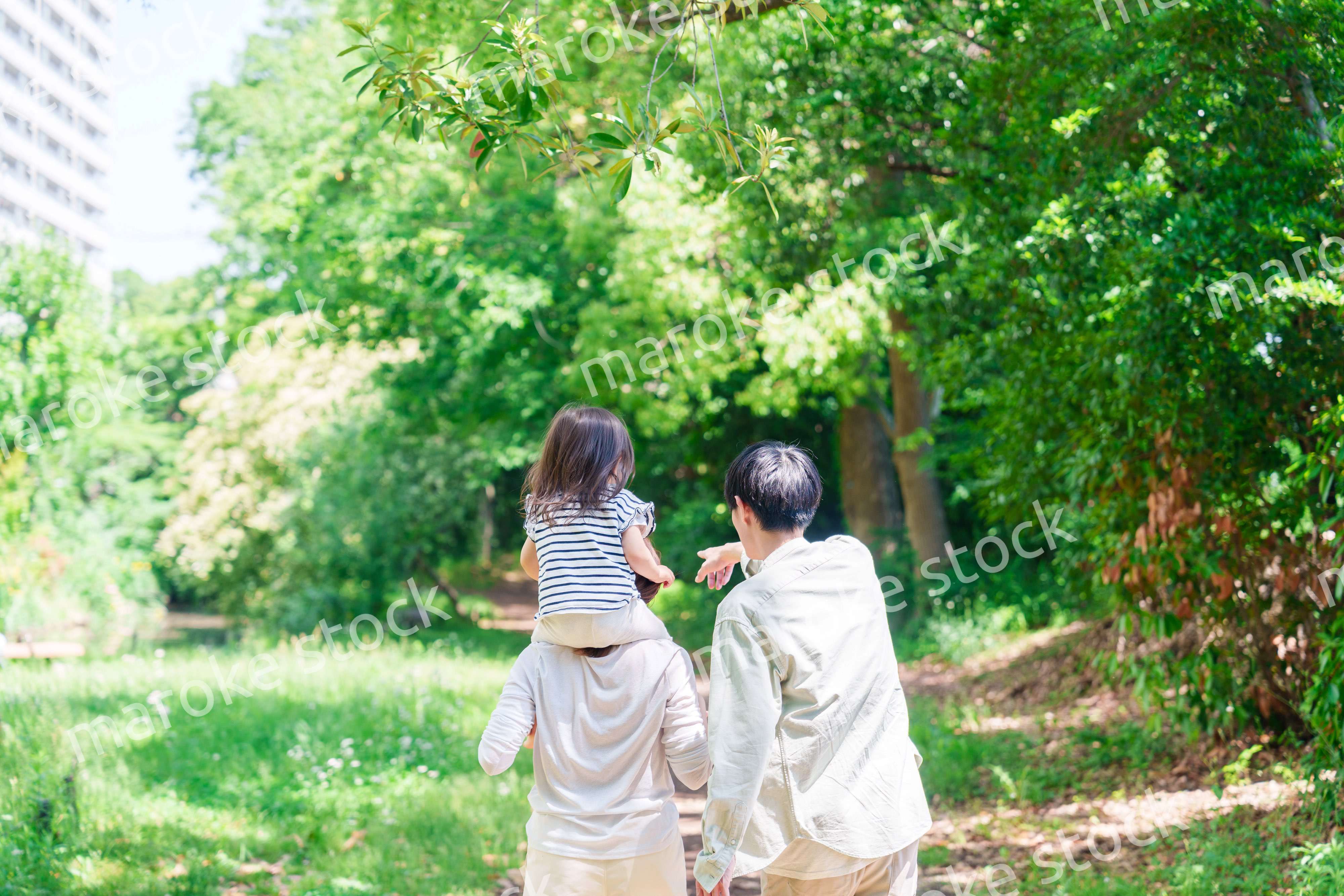子どもを肩車して森の中を歩く家族