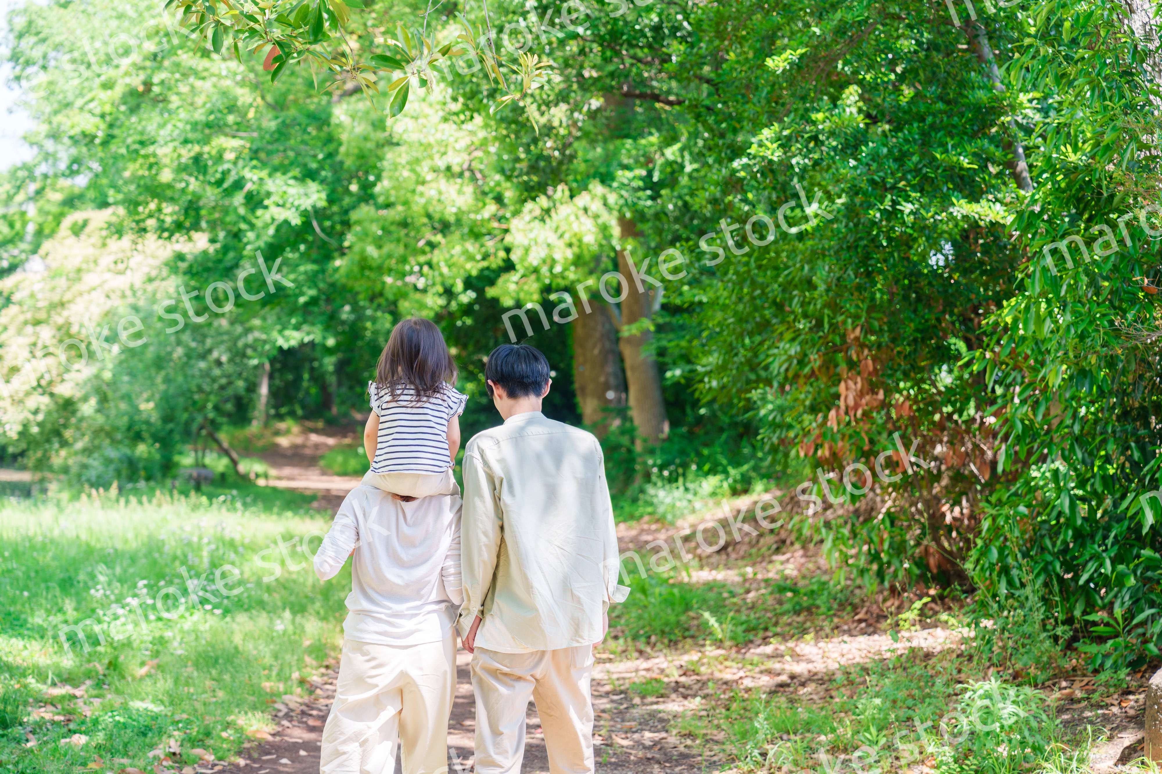 子どもを肩車して森の中を歩く家族