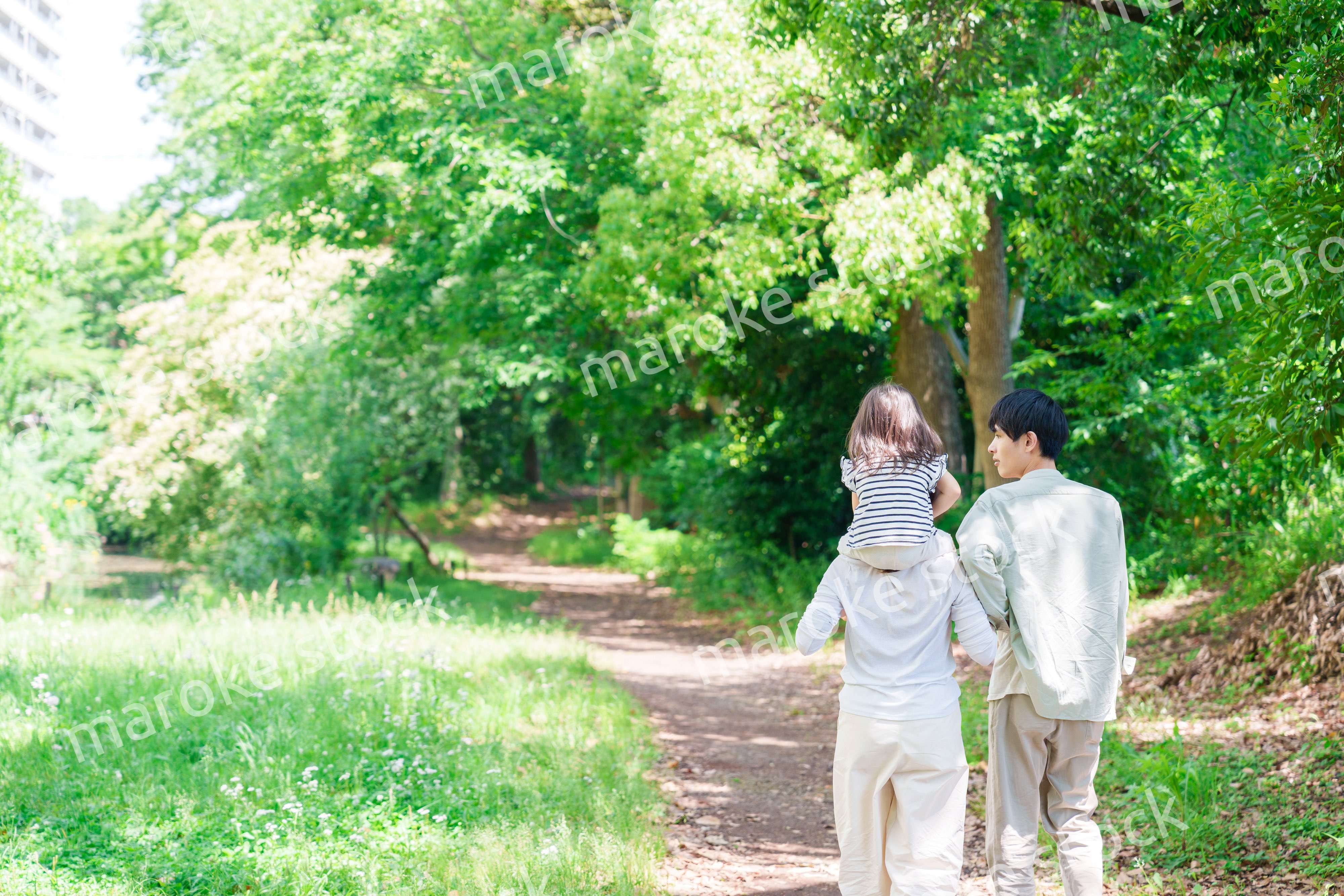 子どもを肩車して森の中を歩く家族