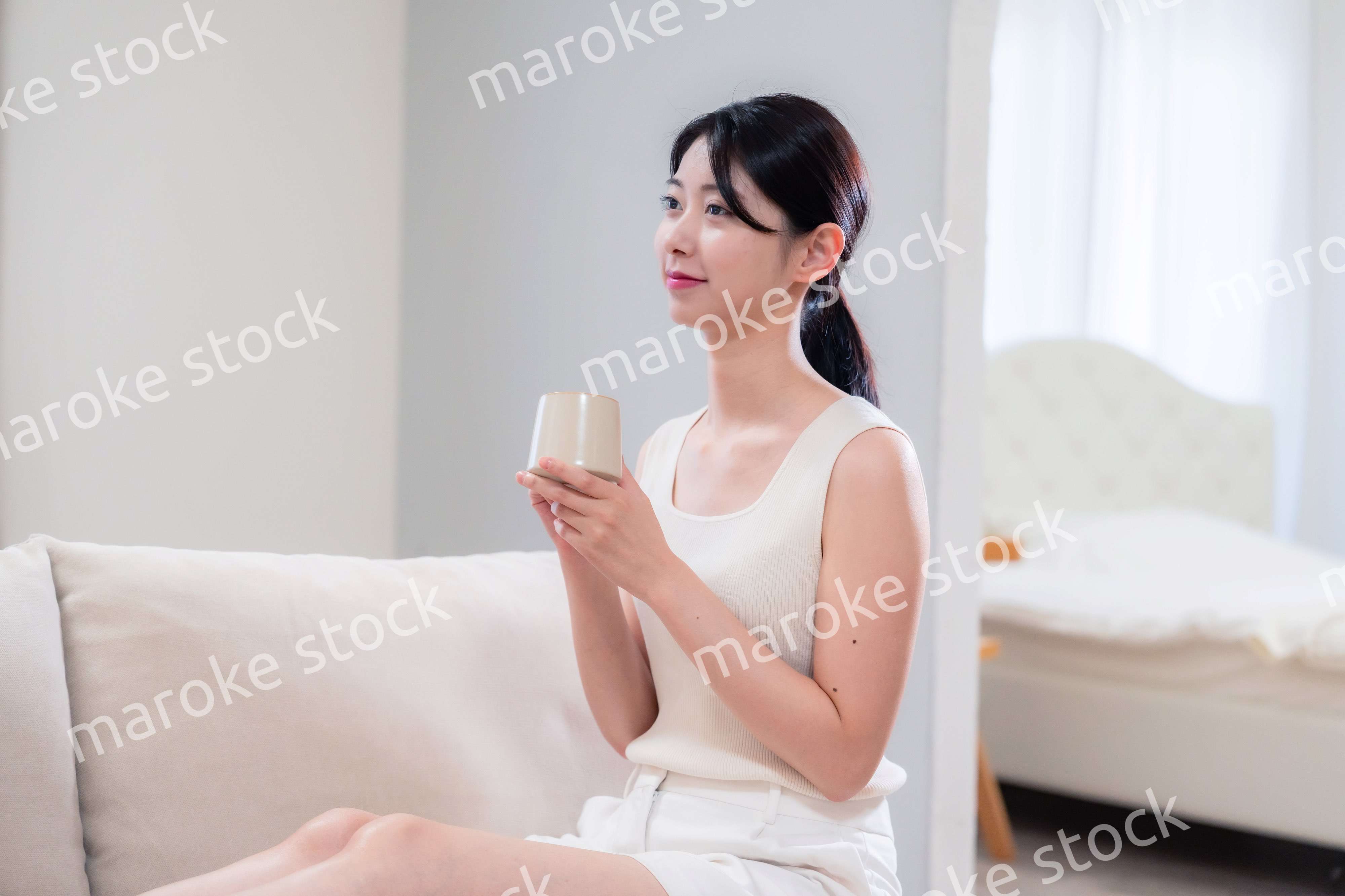 家でソファに座ってリラックスをする若い女性