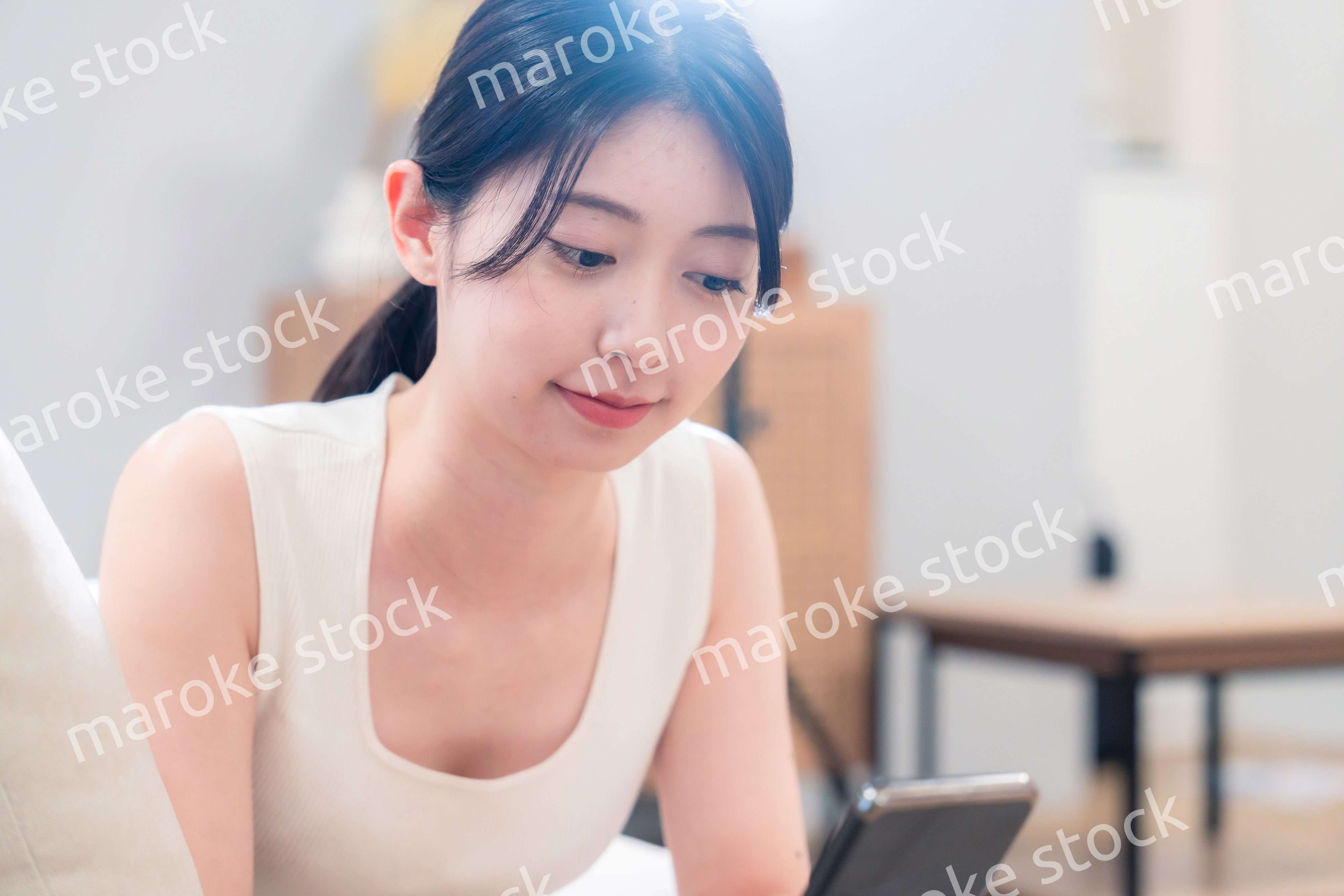 ソファで寝転がってスマホを使う若い女性