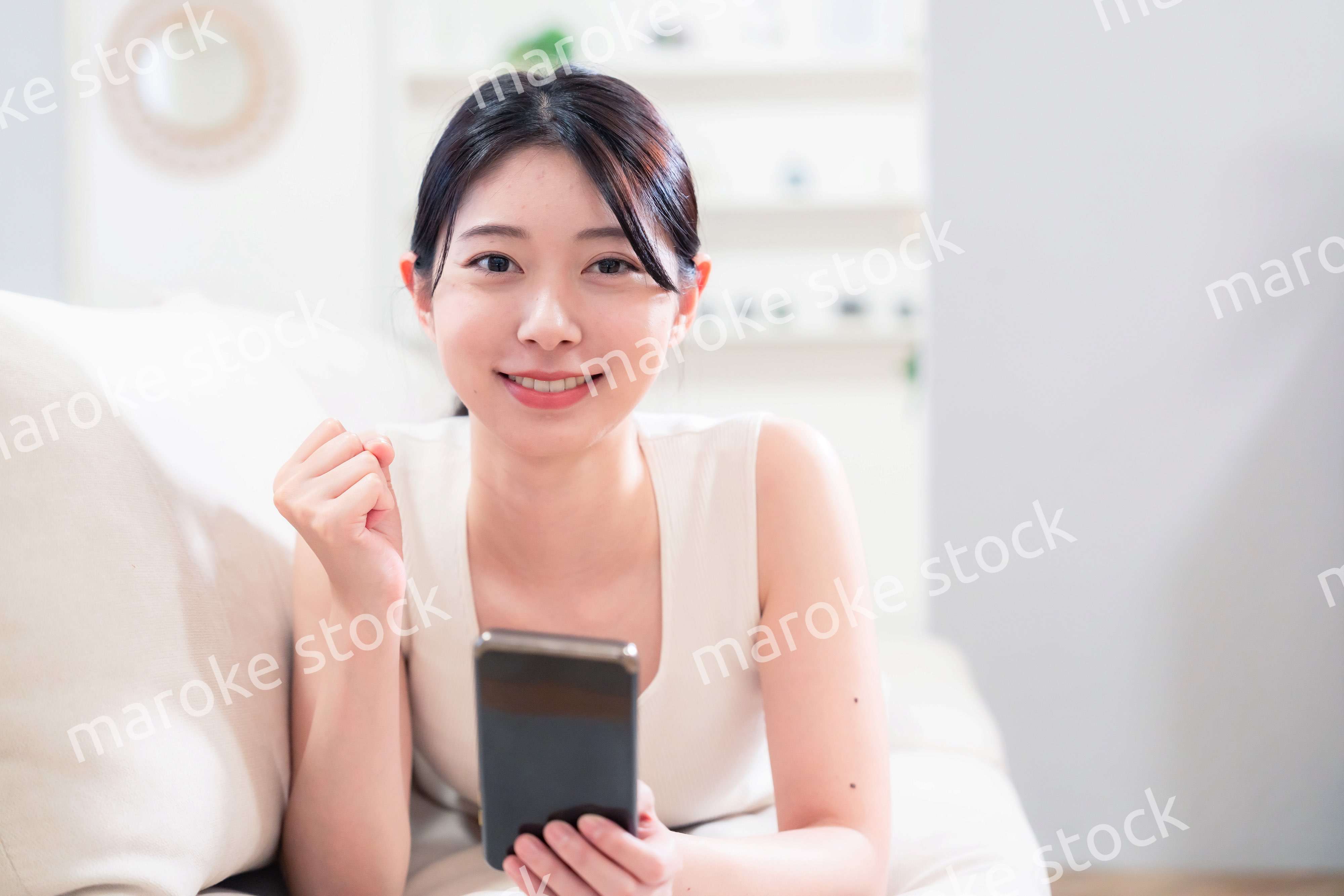 ソファで寝転がってスマホを使う若い女性