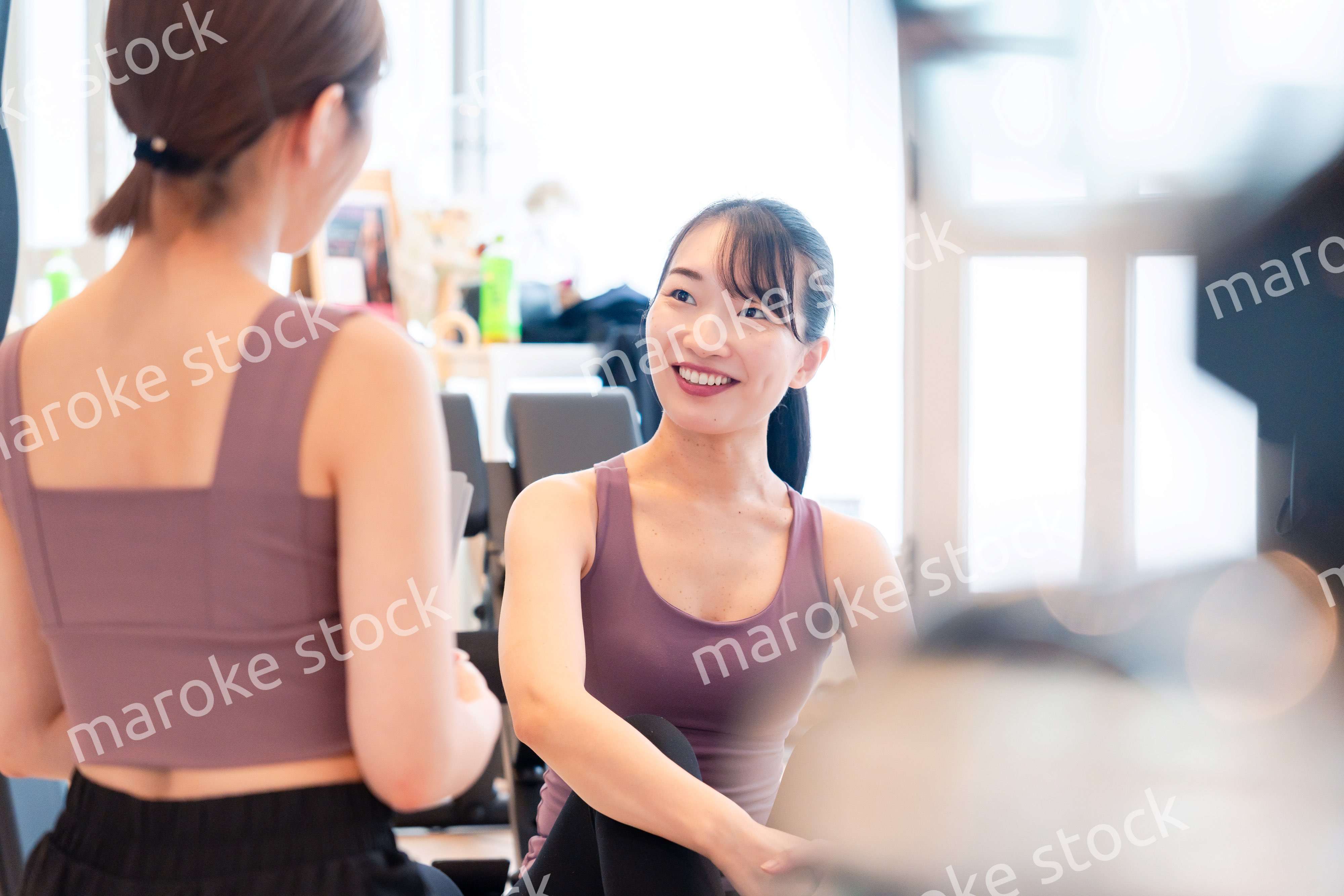 女性トレーナーからの指導を受けて筋トレをする女性