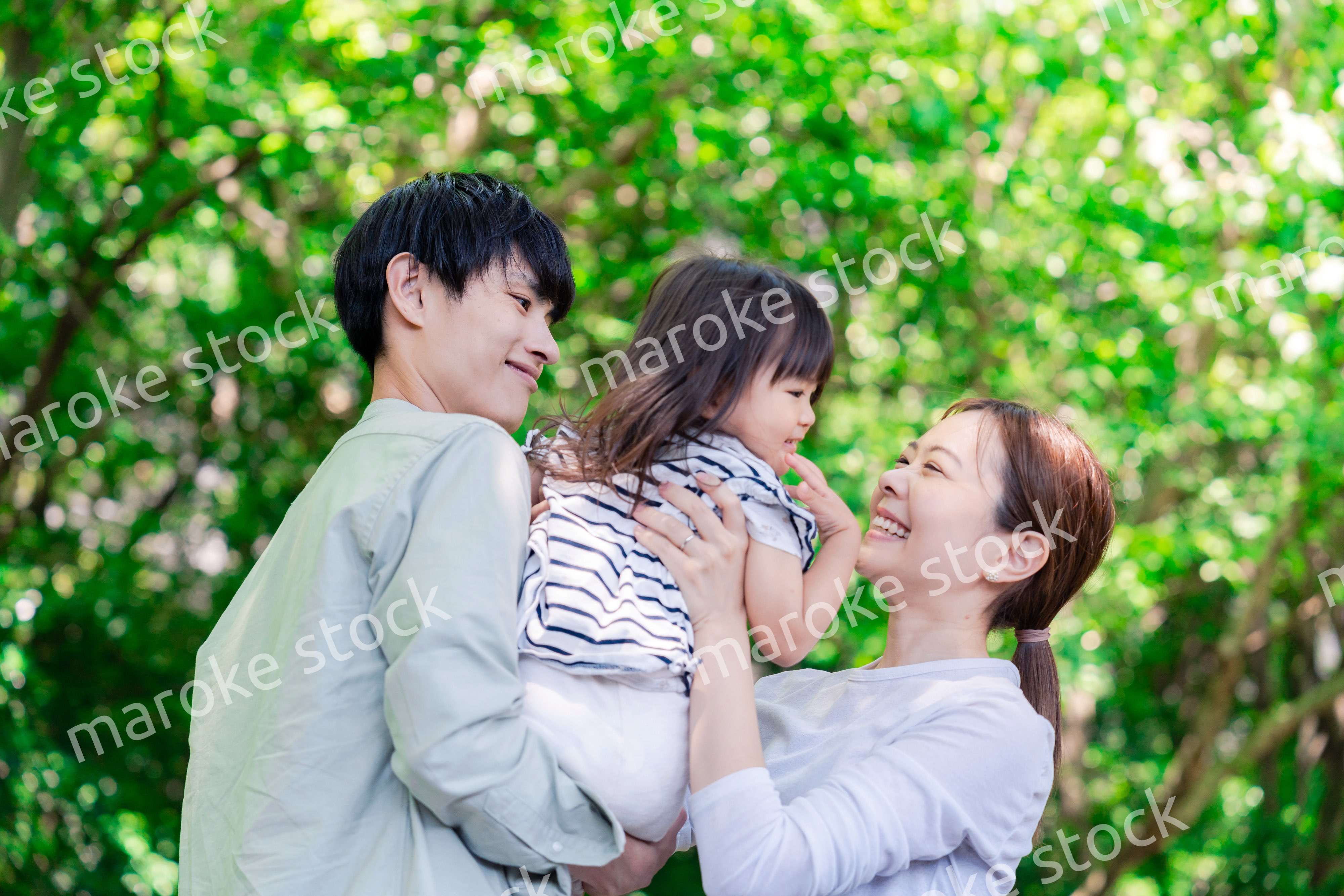 緑の中で子供を抱っこする家族