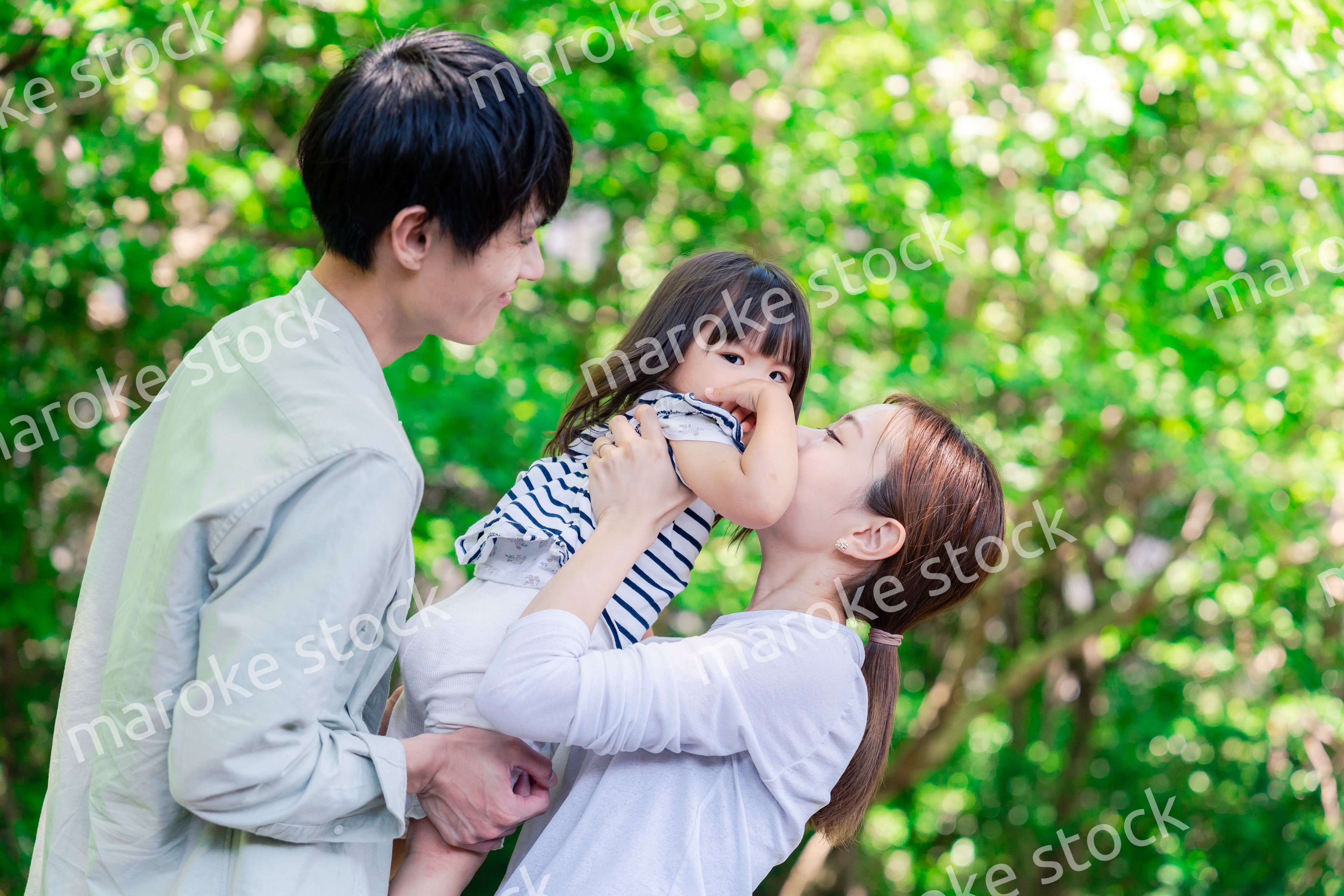 緑の中で子供を抱っこする家族