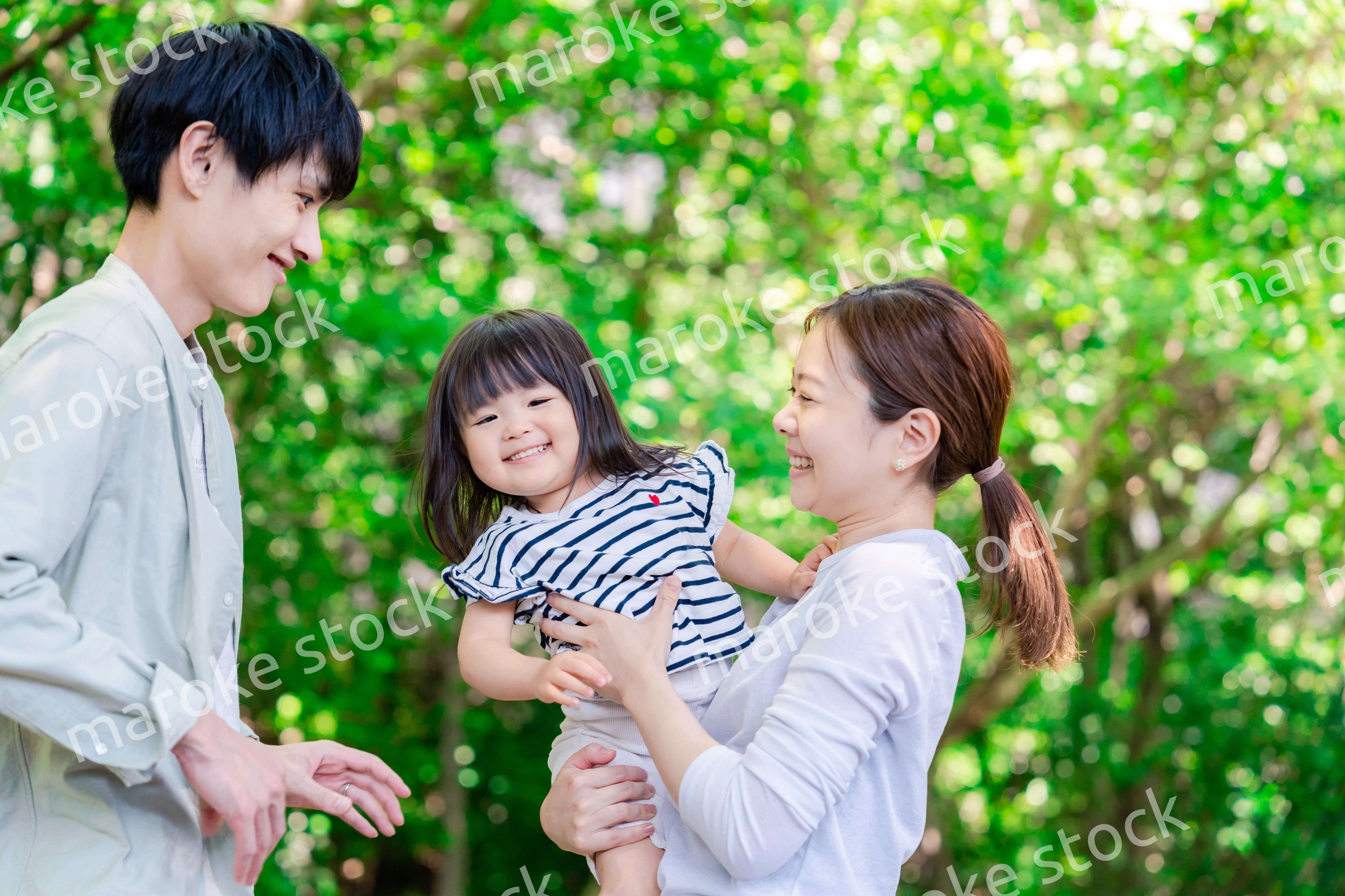 緑の中で子供を抱っこする家族