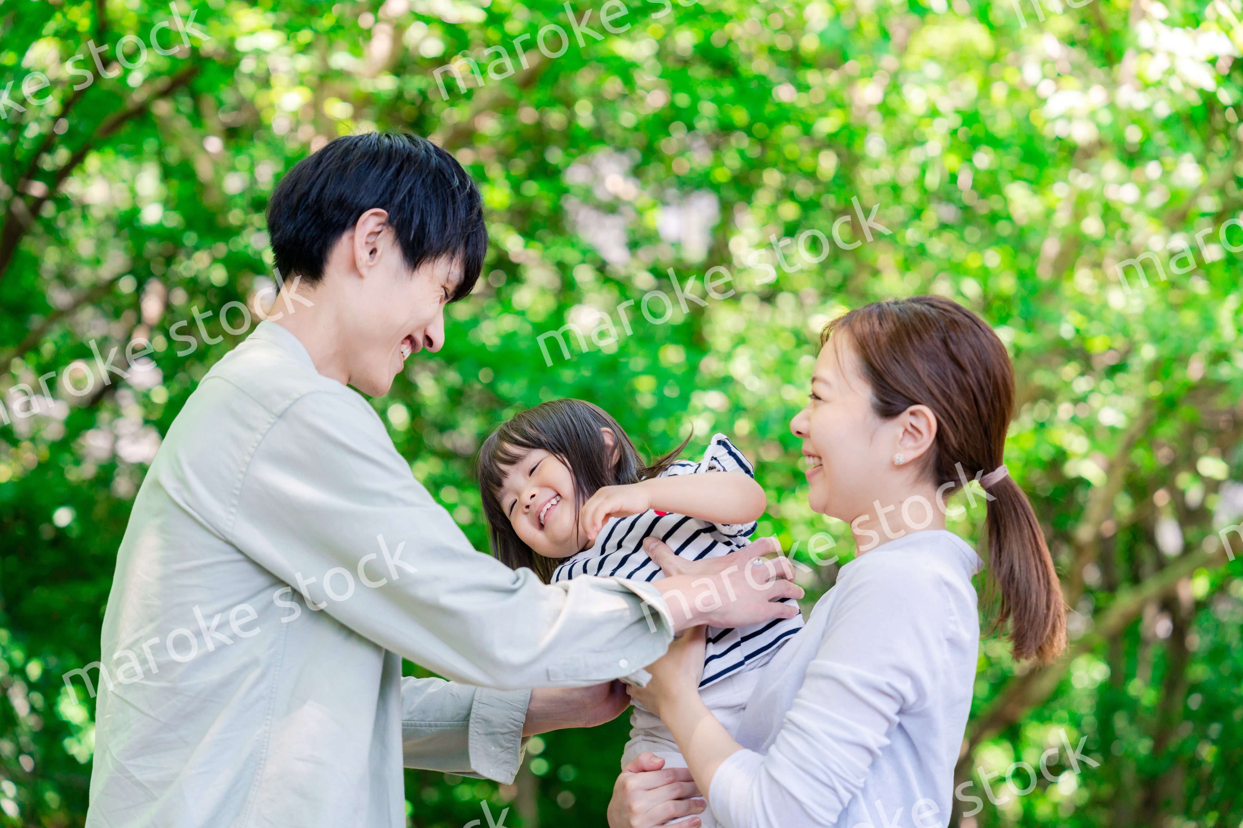 緑の中で子供を抱っこする家族