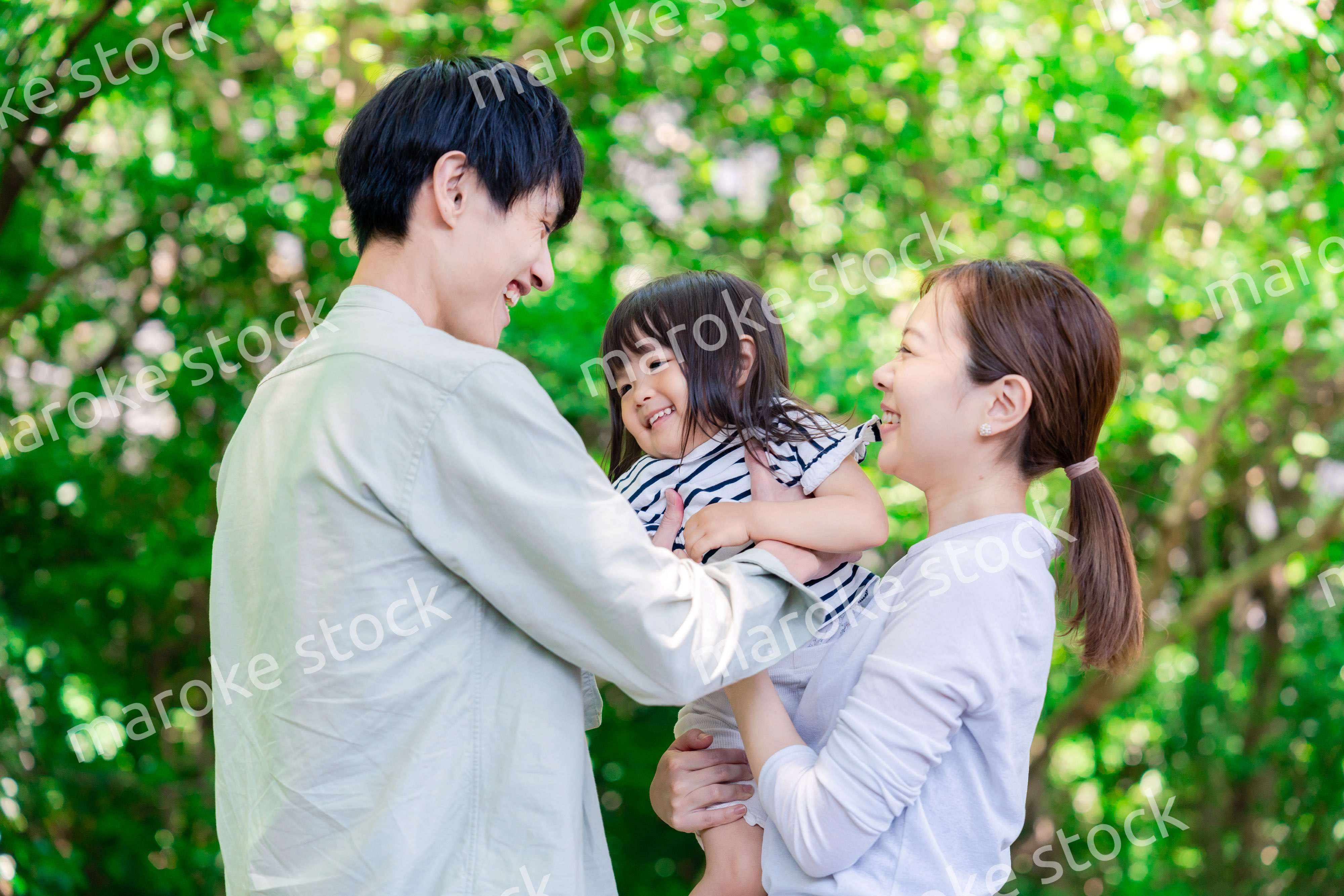 緑の中で子供を抱っこする家族