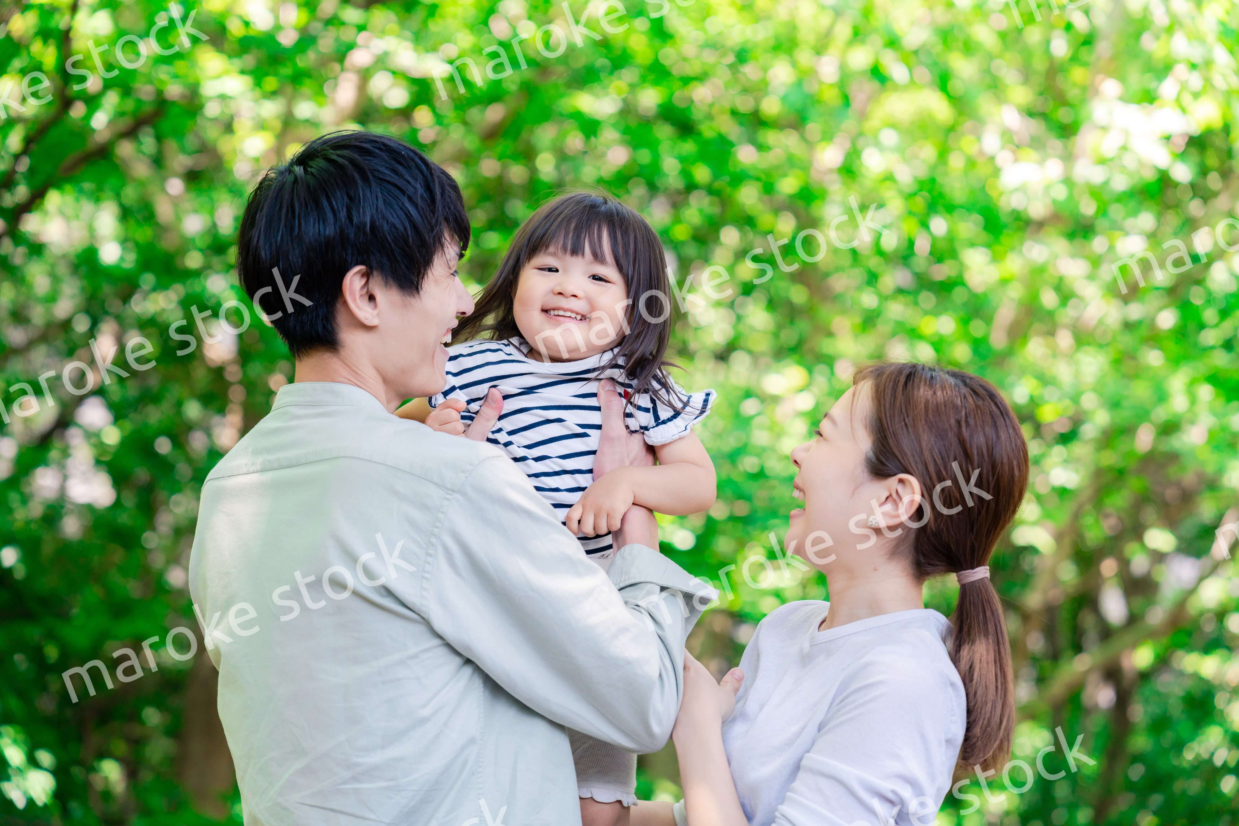 緑の中で子供を抱っこする家族