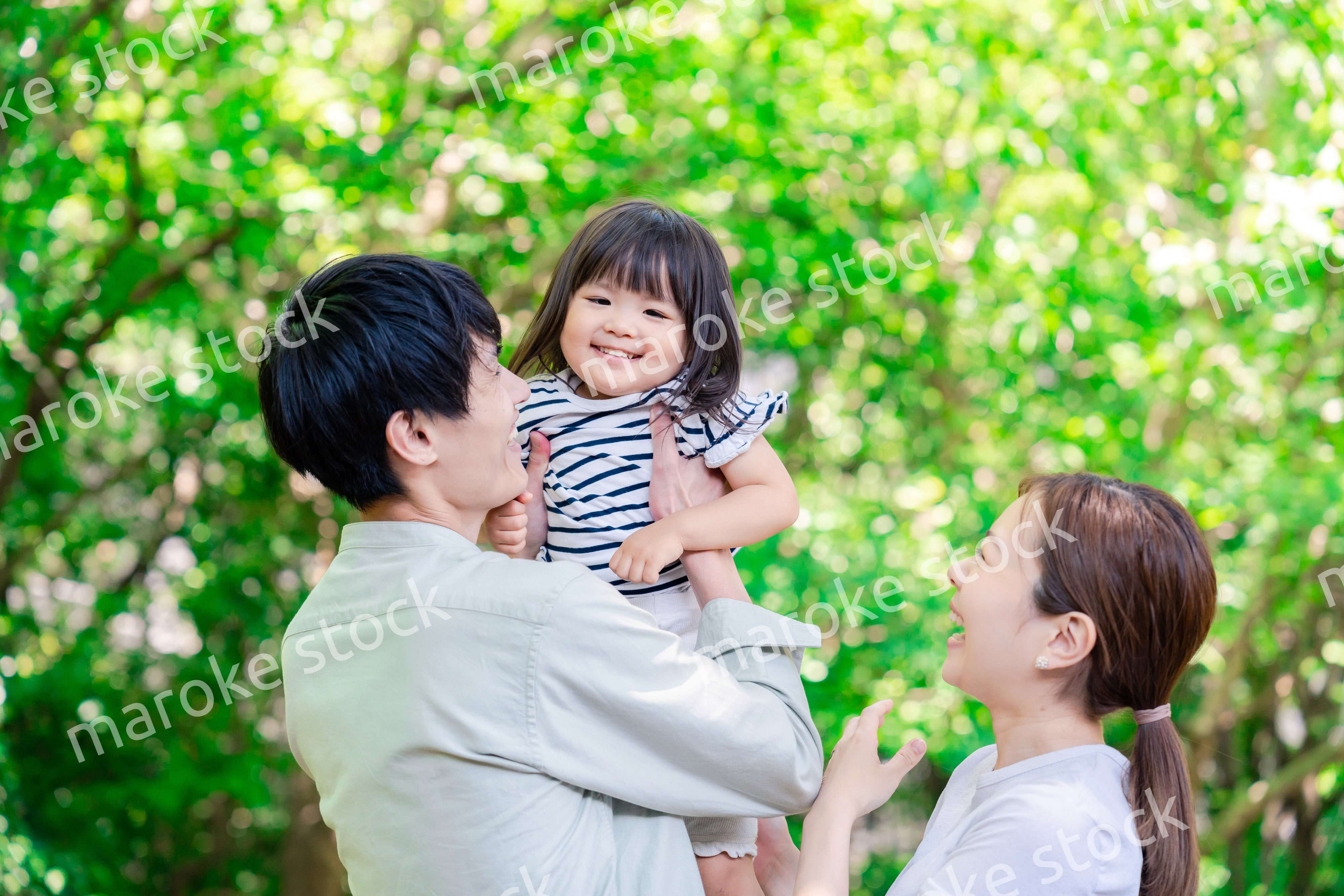 緑の中で子供を抱っこする家族