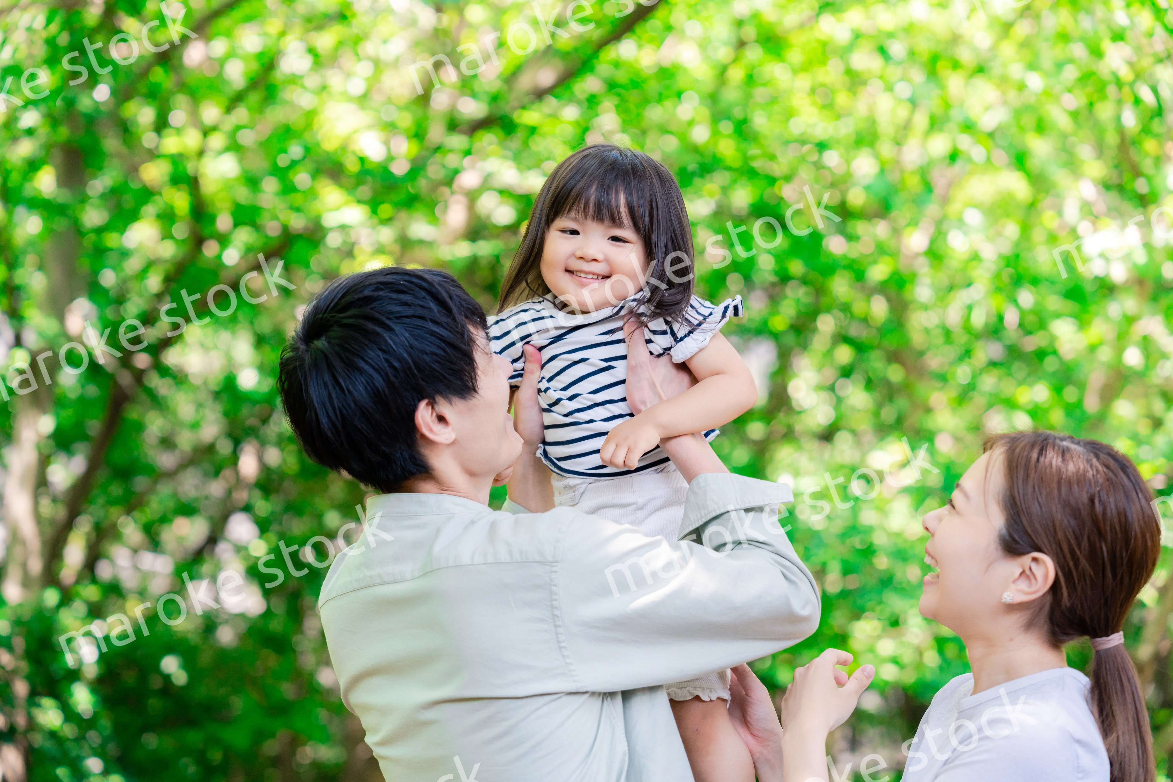 緑の中で子供を抱っこする家族