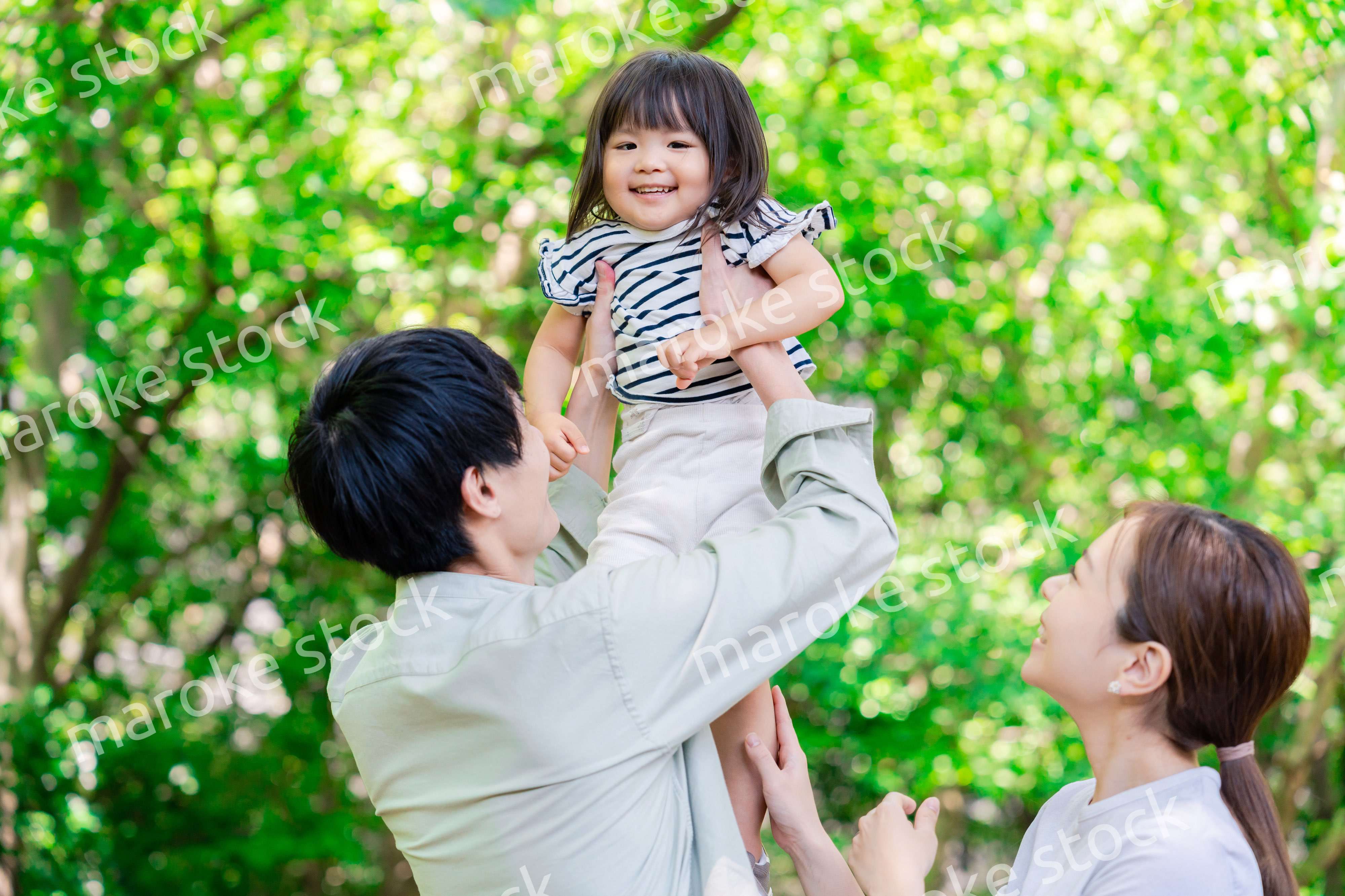 緑の中で子供を抱っこする家族