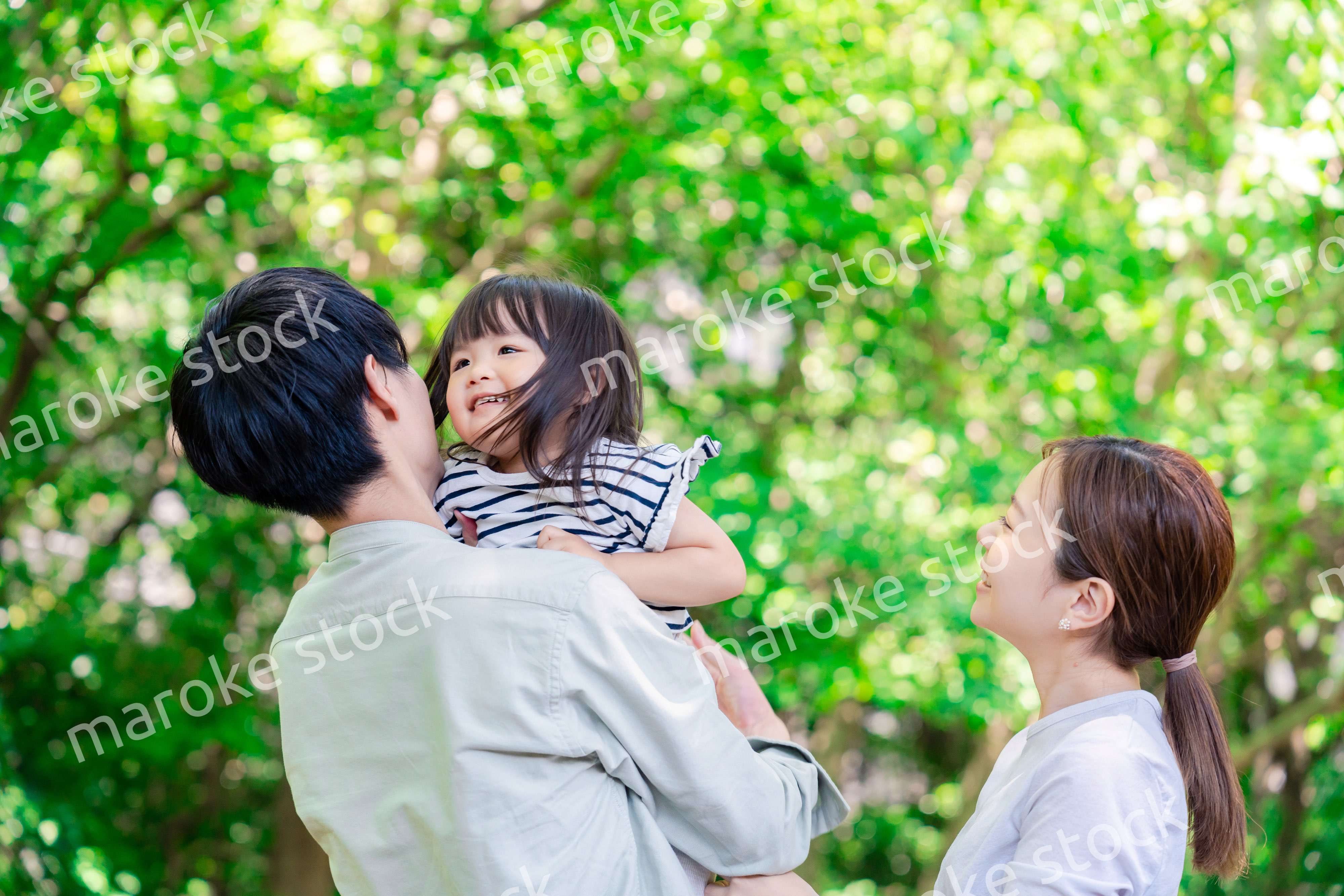 緑の中で子供を抱っこする家族