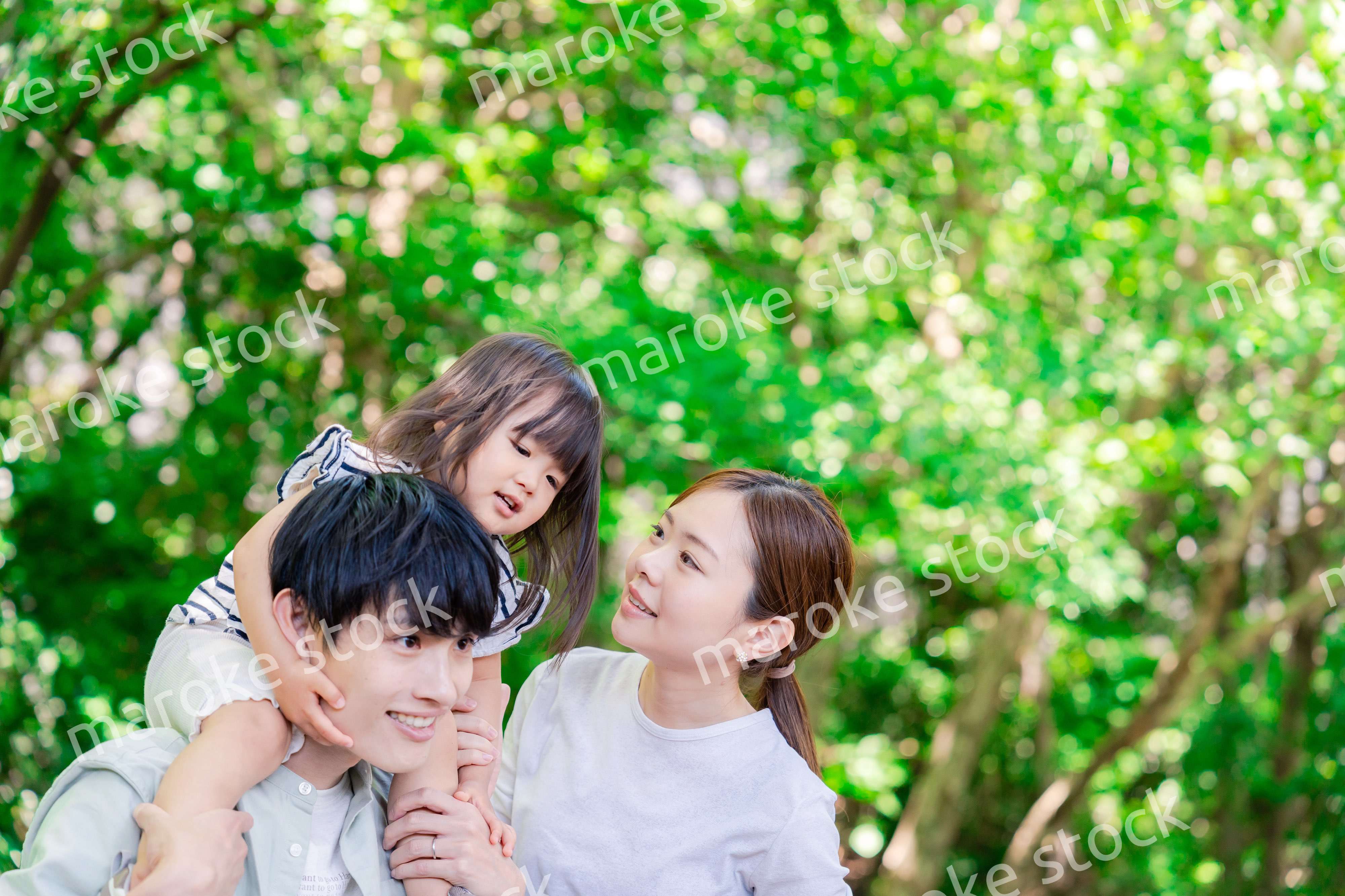 緑の中で子供を抱っこする家族