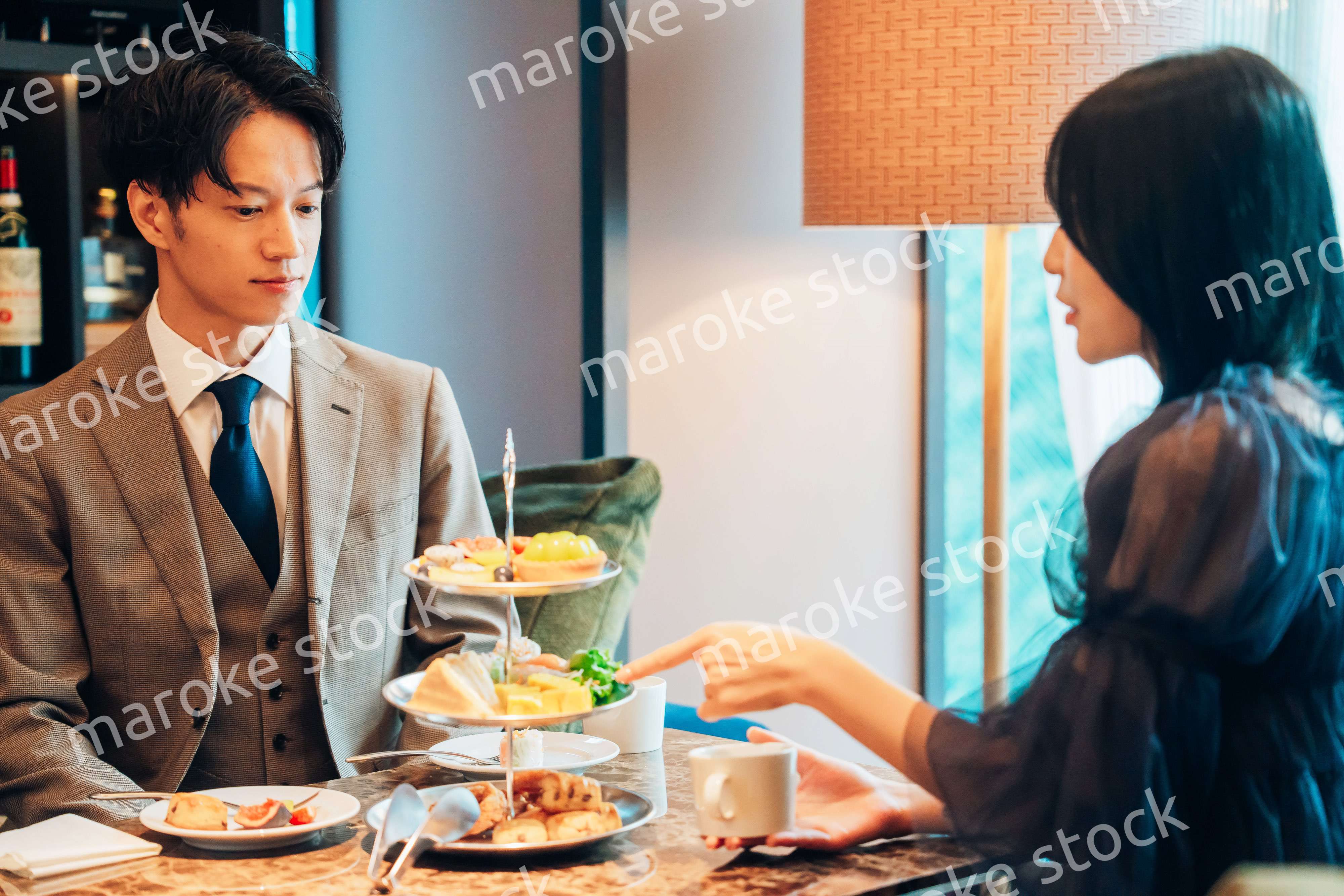 若い女性とアフタヌーンティーを楽しむ男性