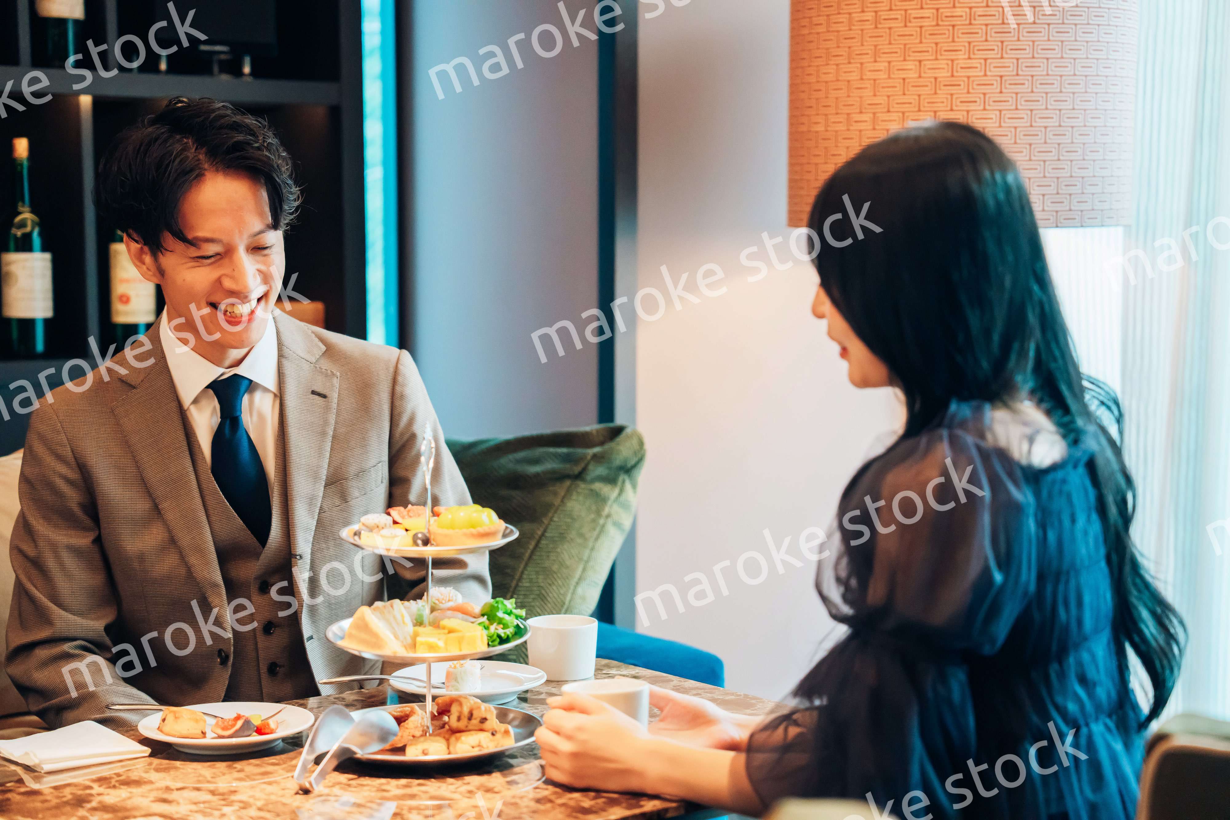 若い女性とアフタヌーンティーを楽しむ男性