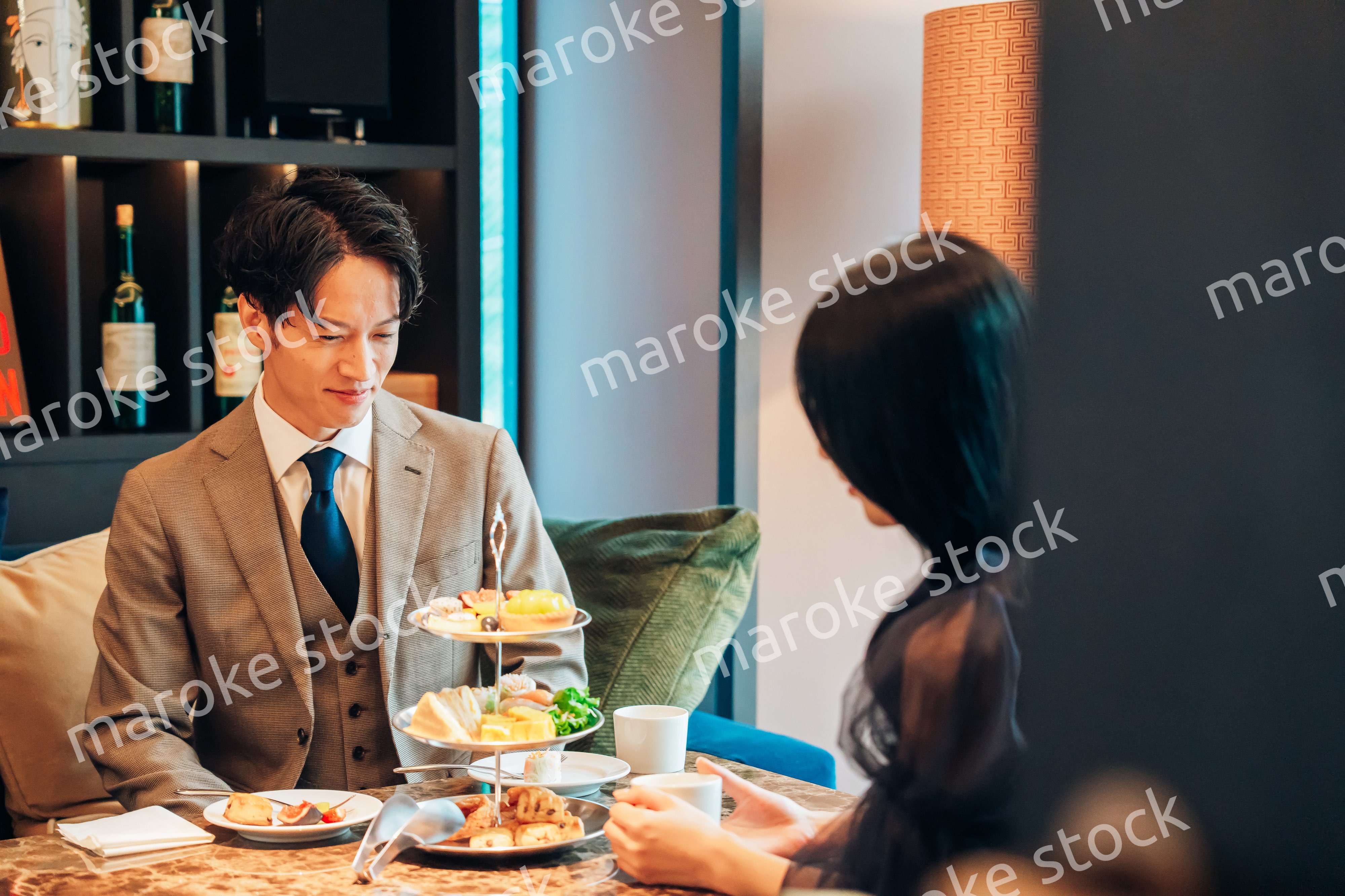 若い女性とアフタヌーンティーを楽しむ男性