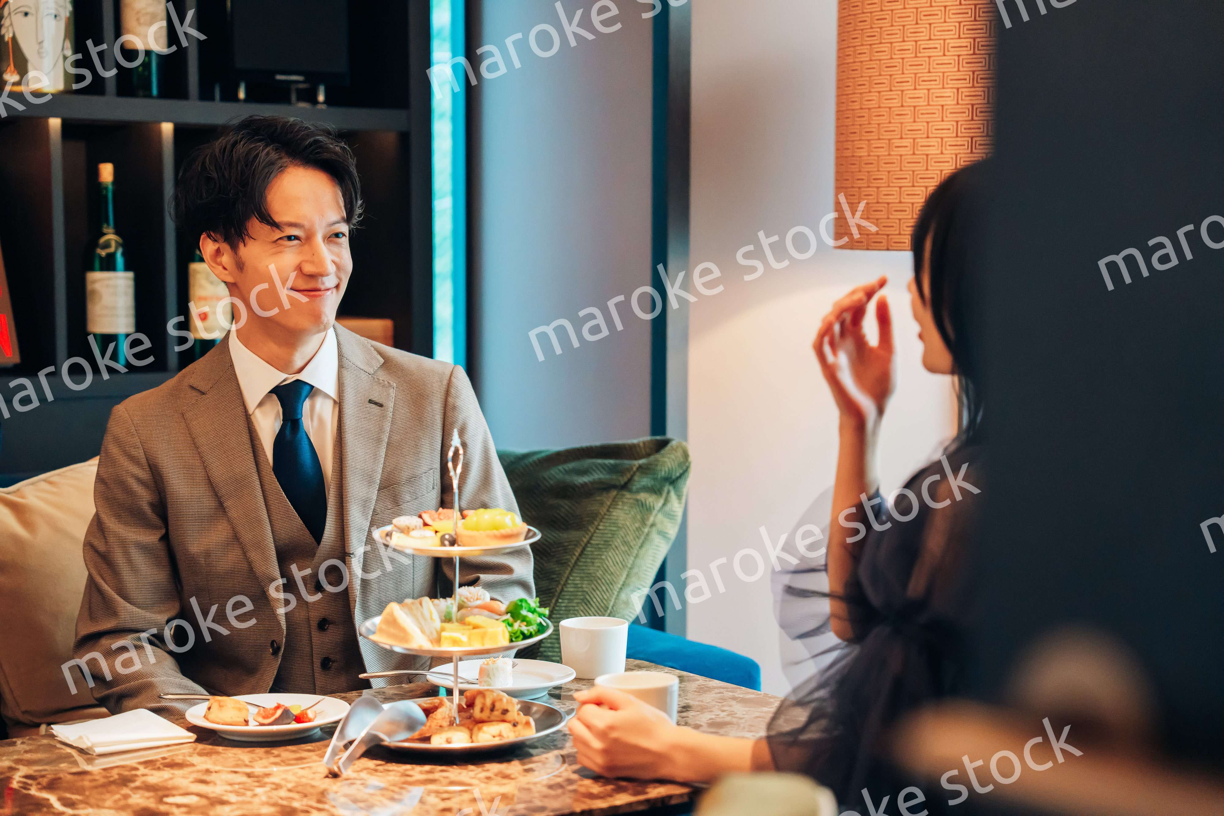 若い女性とアフタヌーンティーを楽しむ男性