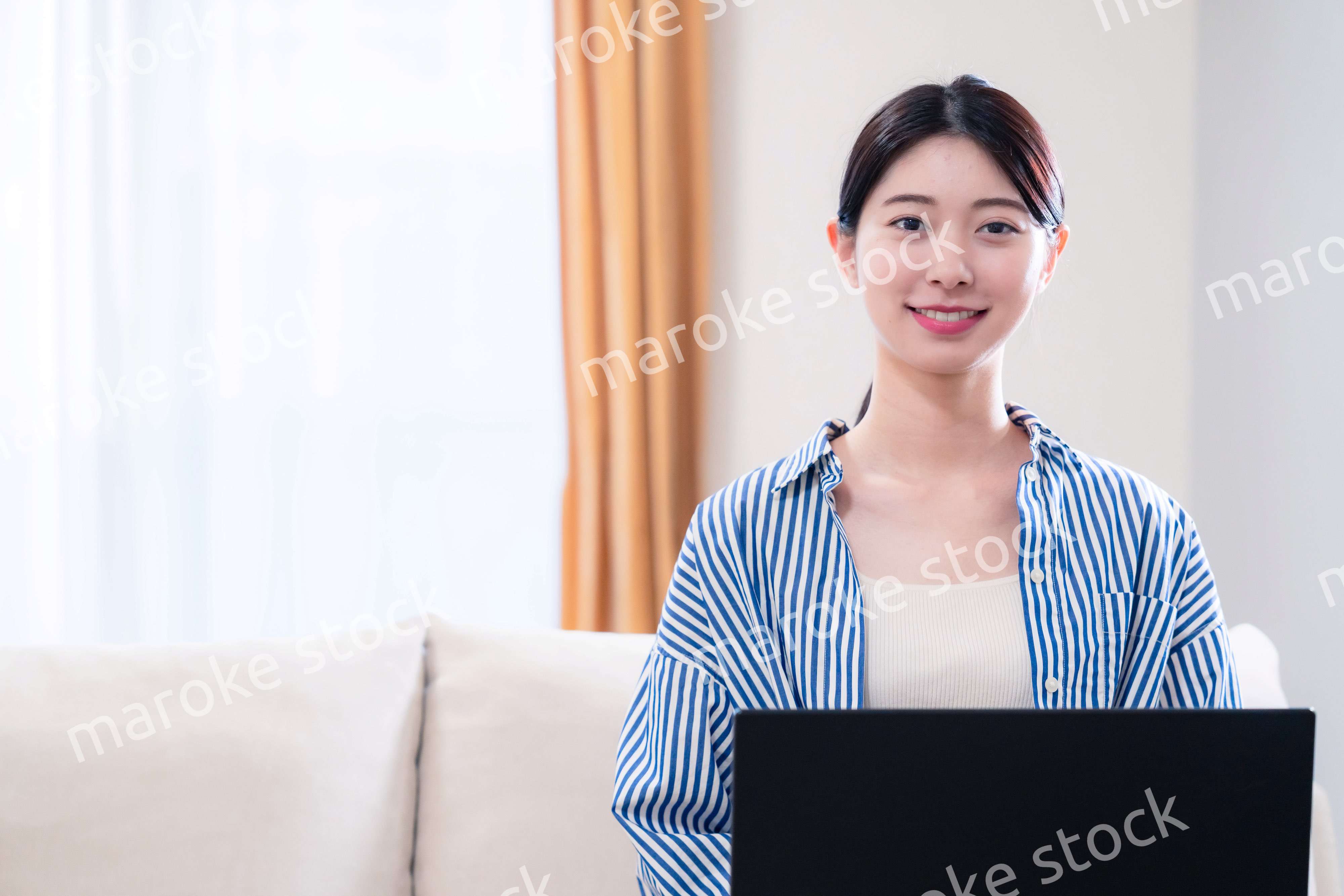 家でリラックスをしてパソコンを使う若い女性