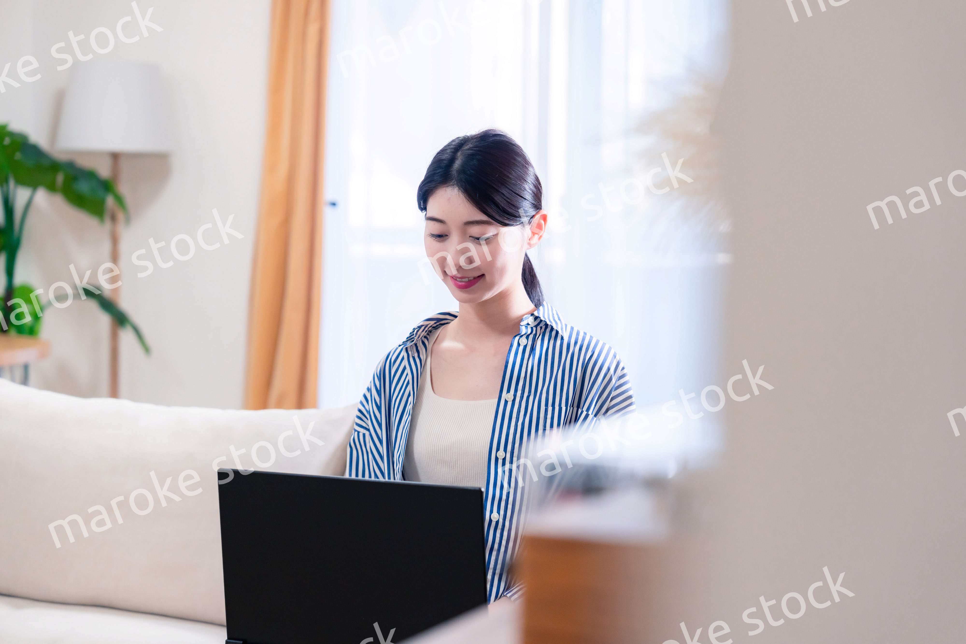 家でリラックスをしてパソコンを使う若い女性