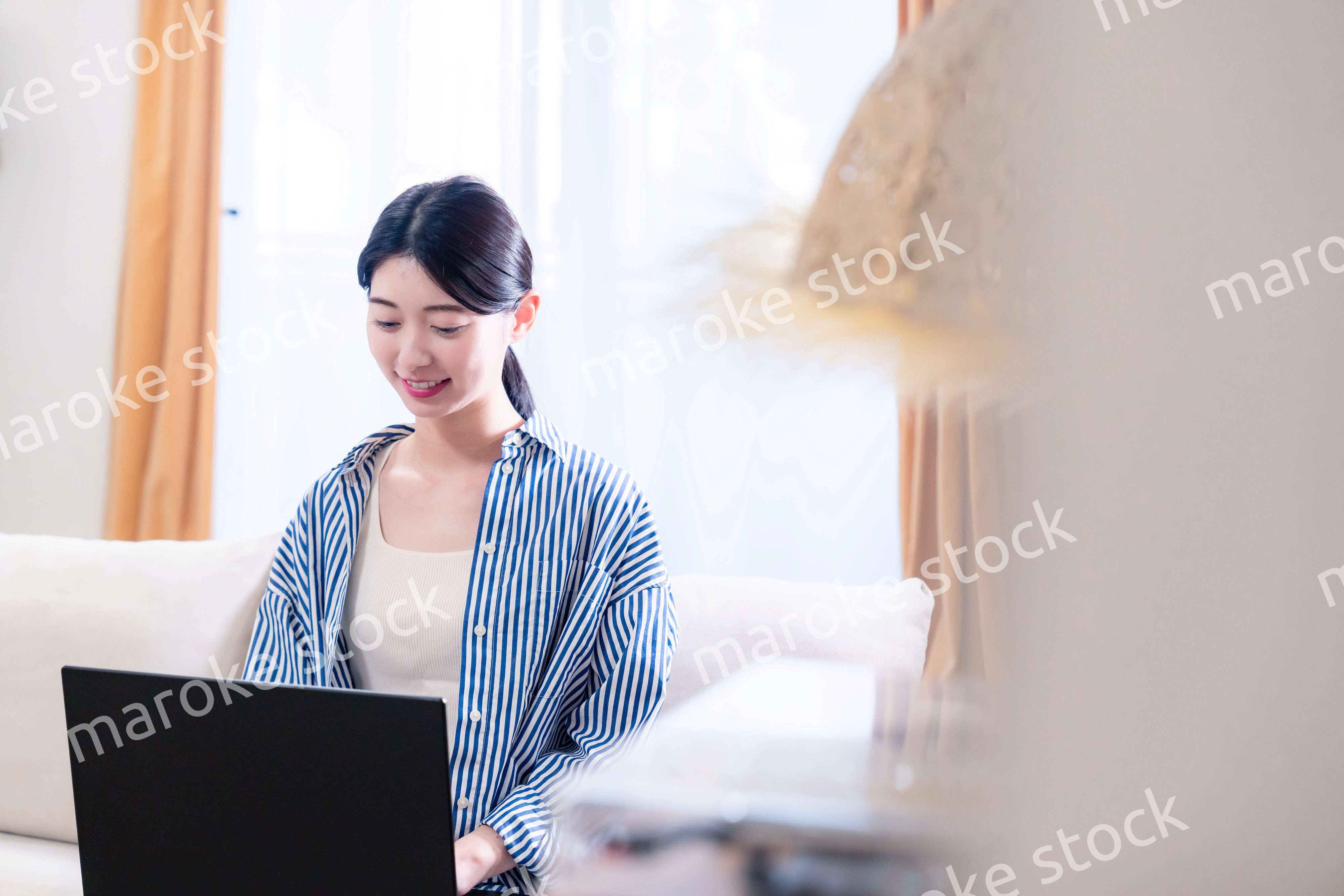 家でリラックスをしてパソコンを使う若い女性