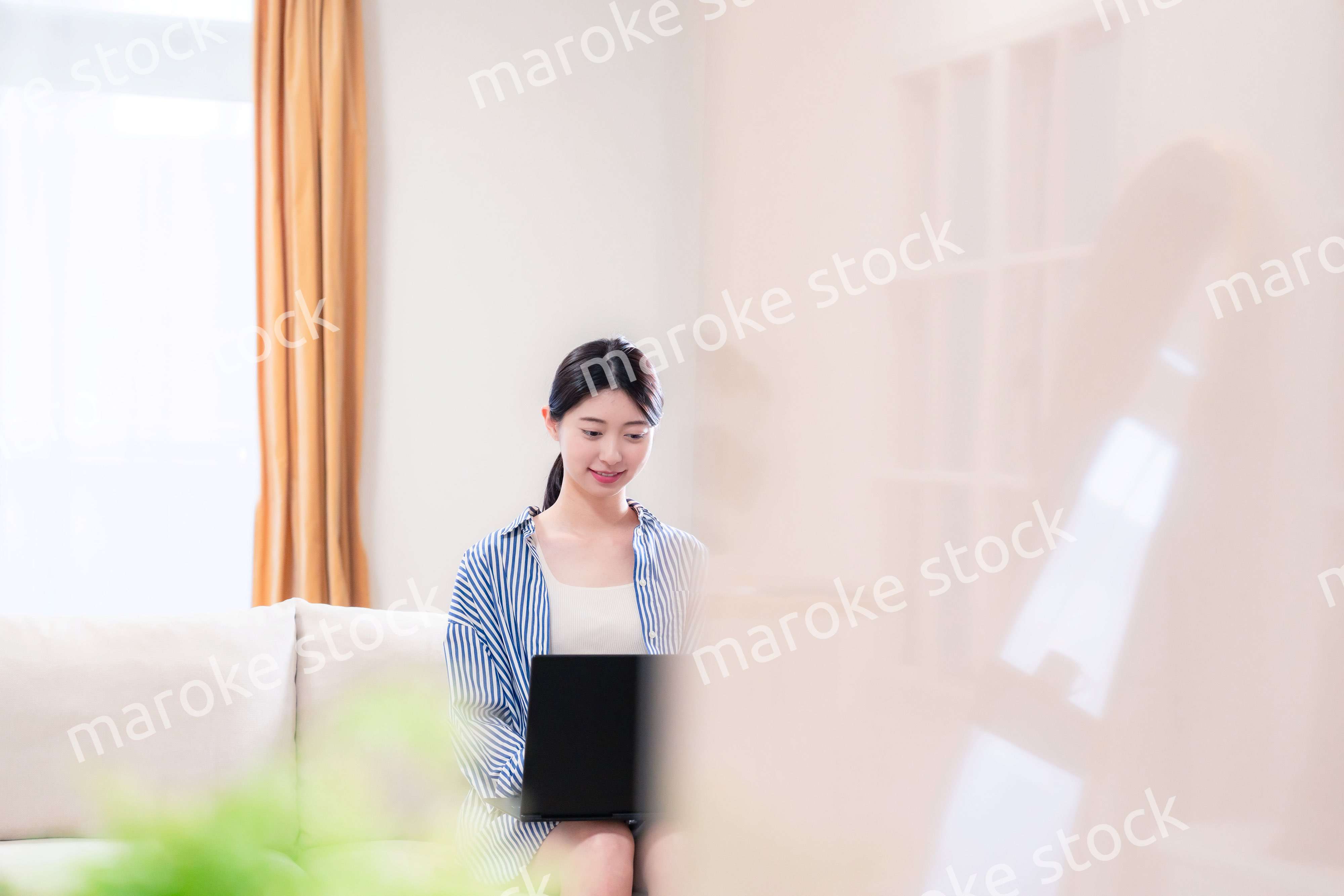 家でリラックスをしてパソコンを使う若い女性