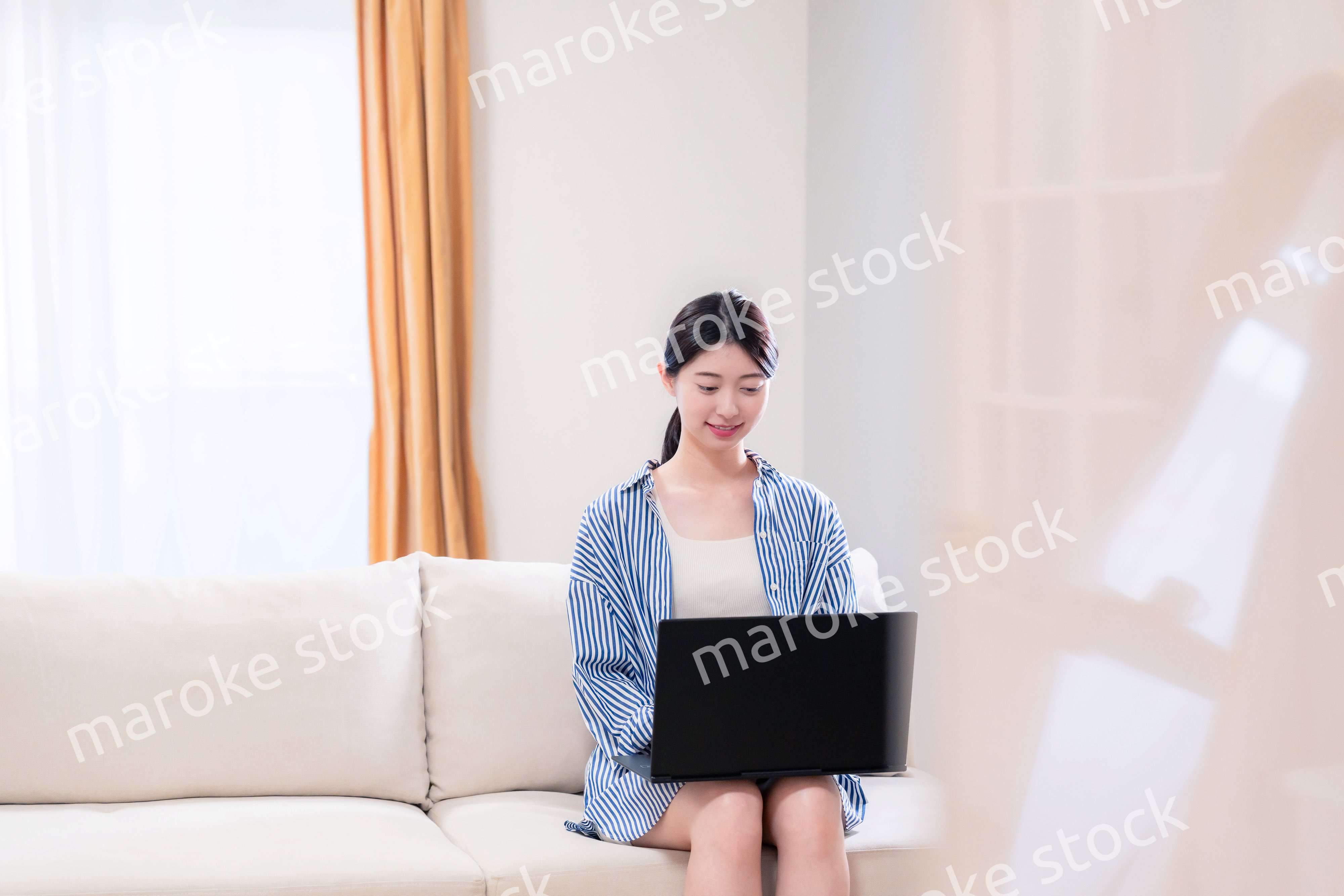 家でリラックスをしてパソコンを使う若い女性