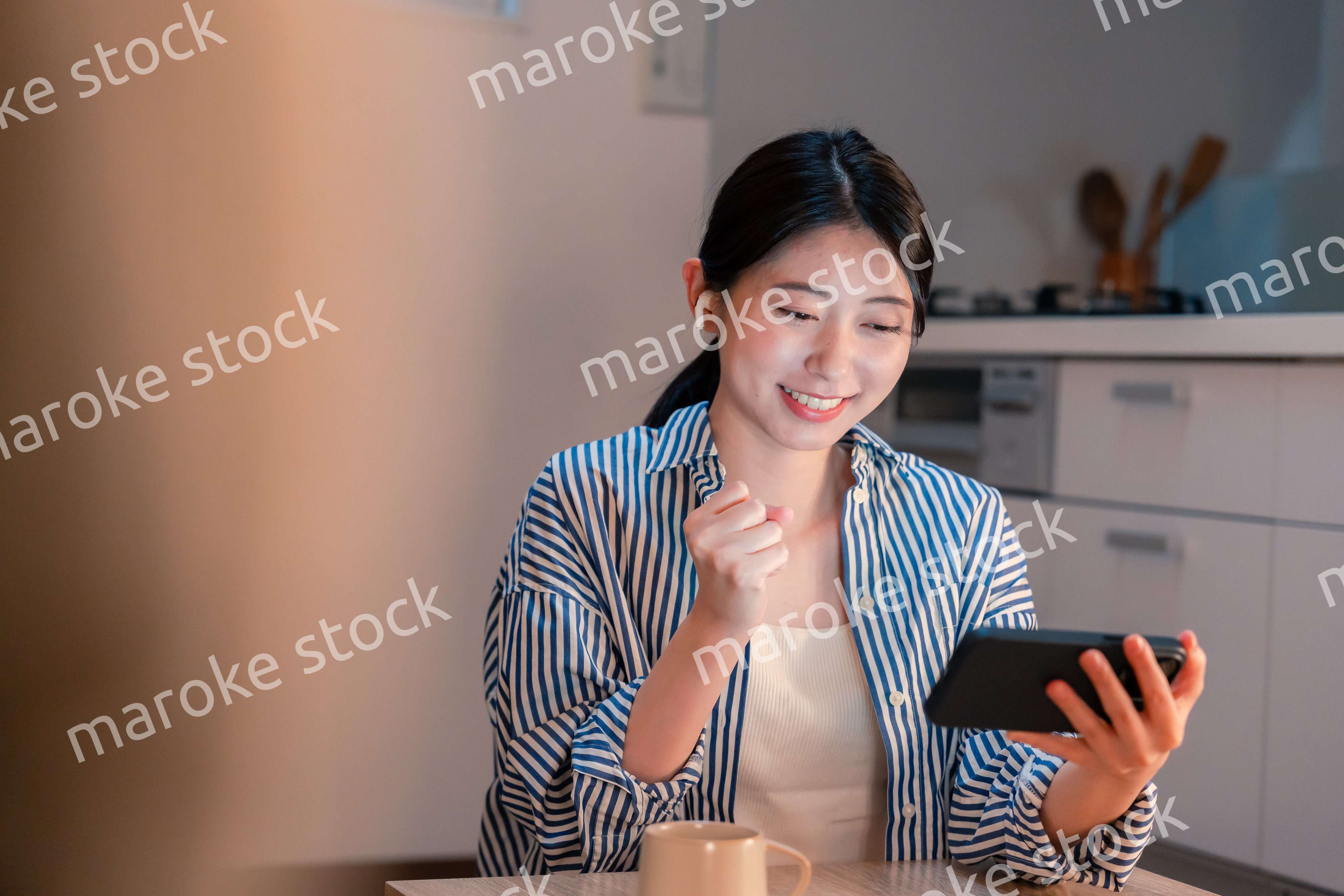 夜に家でスマホでスポーツ観戦をする若い女性