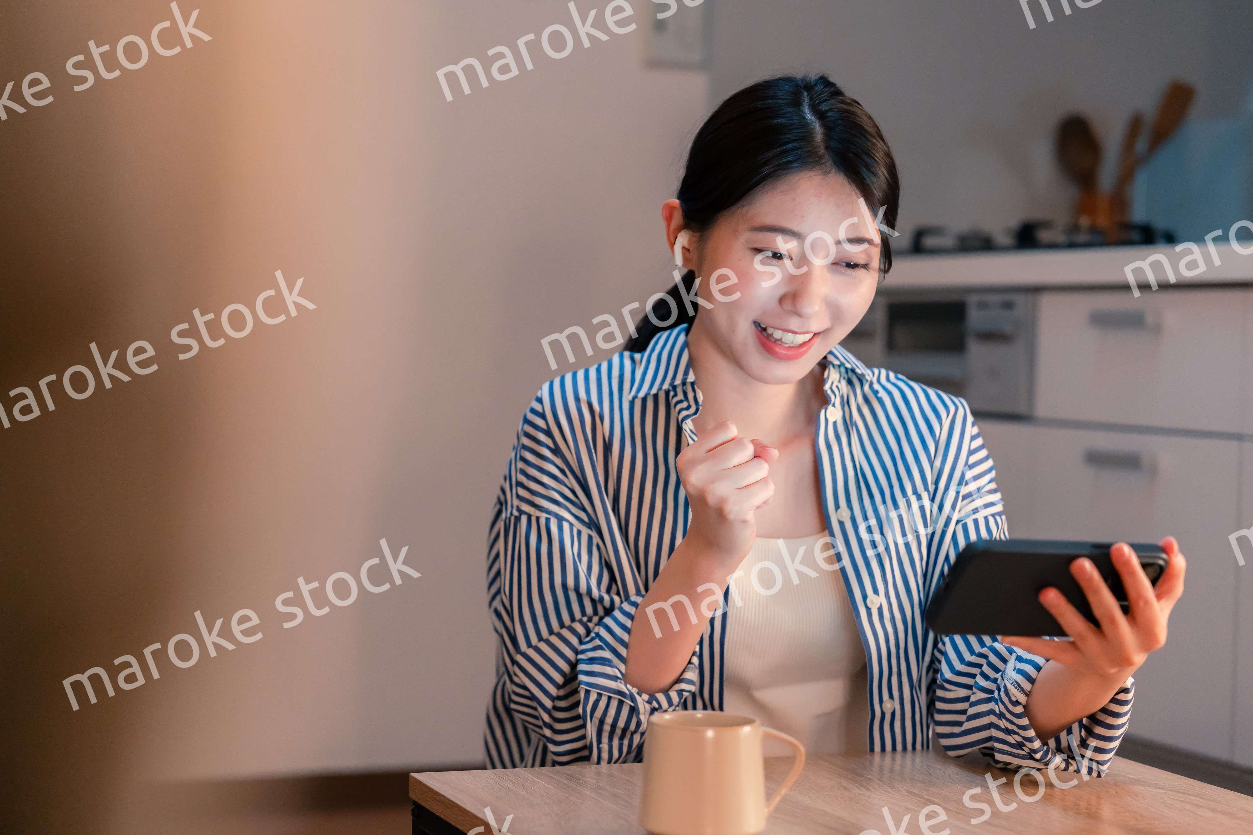 夜に家でスマホでスポーツ観戦をする若い女性