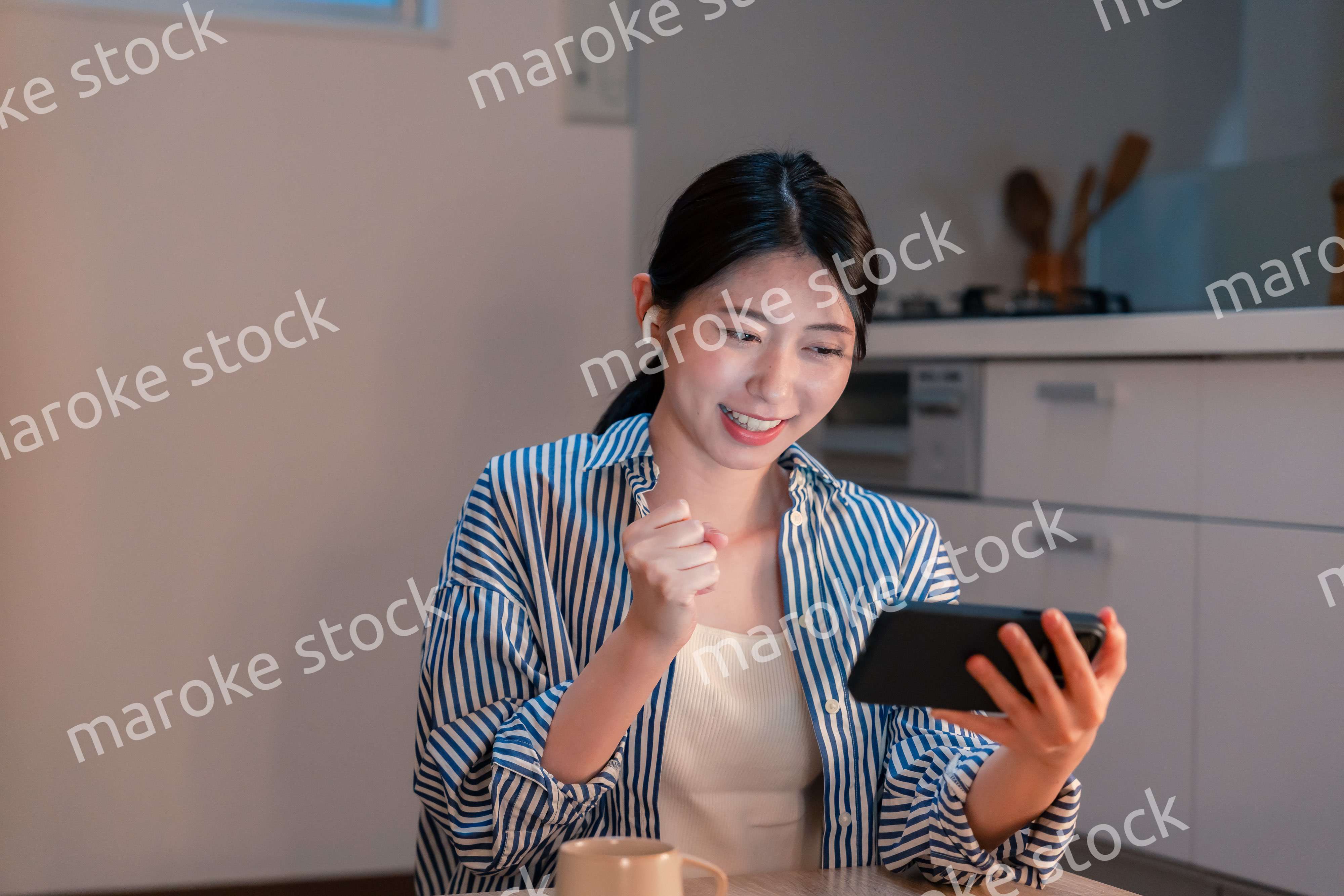 夜に家でスマホでスポーツ観戦をする若い女性