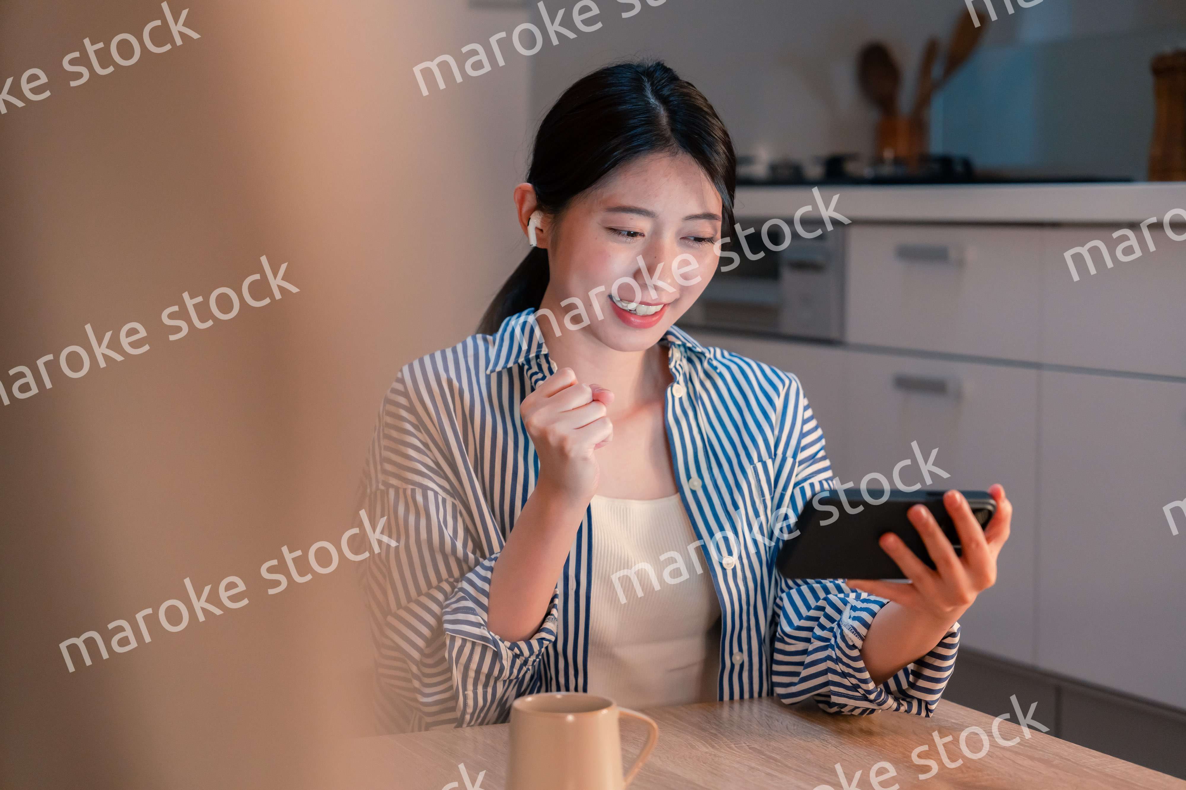 夜に家でスマホでスポーツ観戦をする若い女性