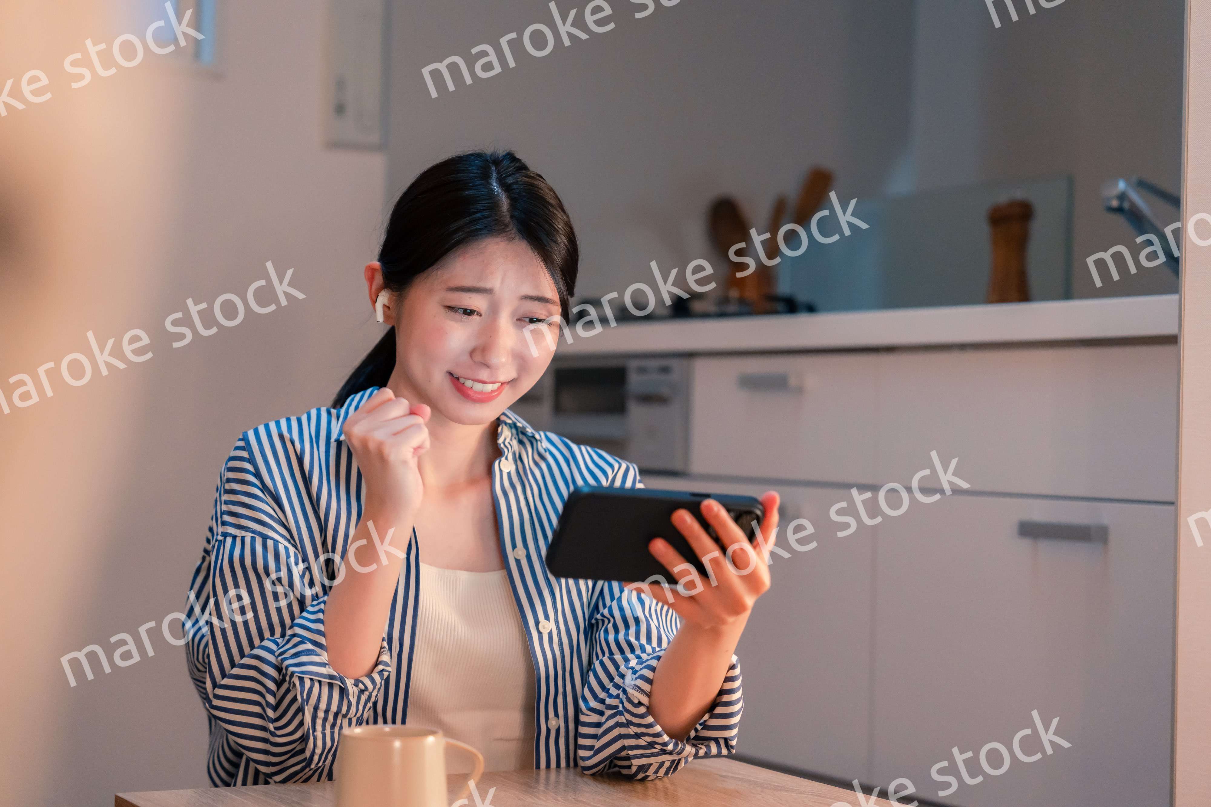 夜に家でスマホでスポーツ観戦をする若い女性