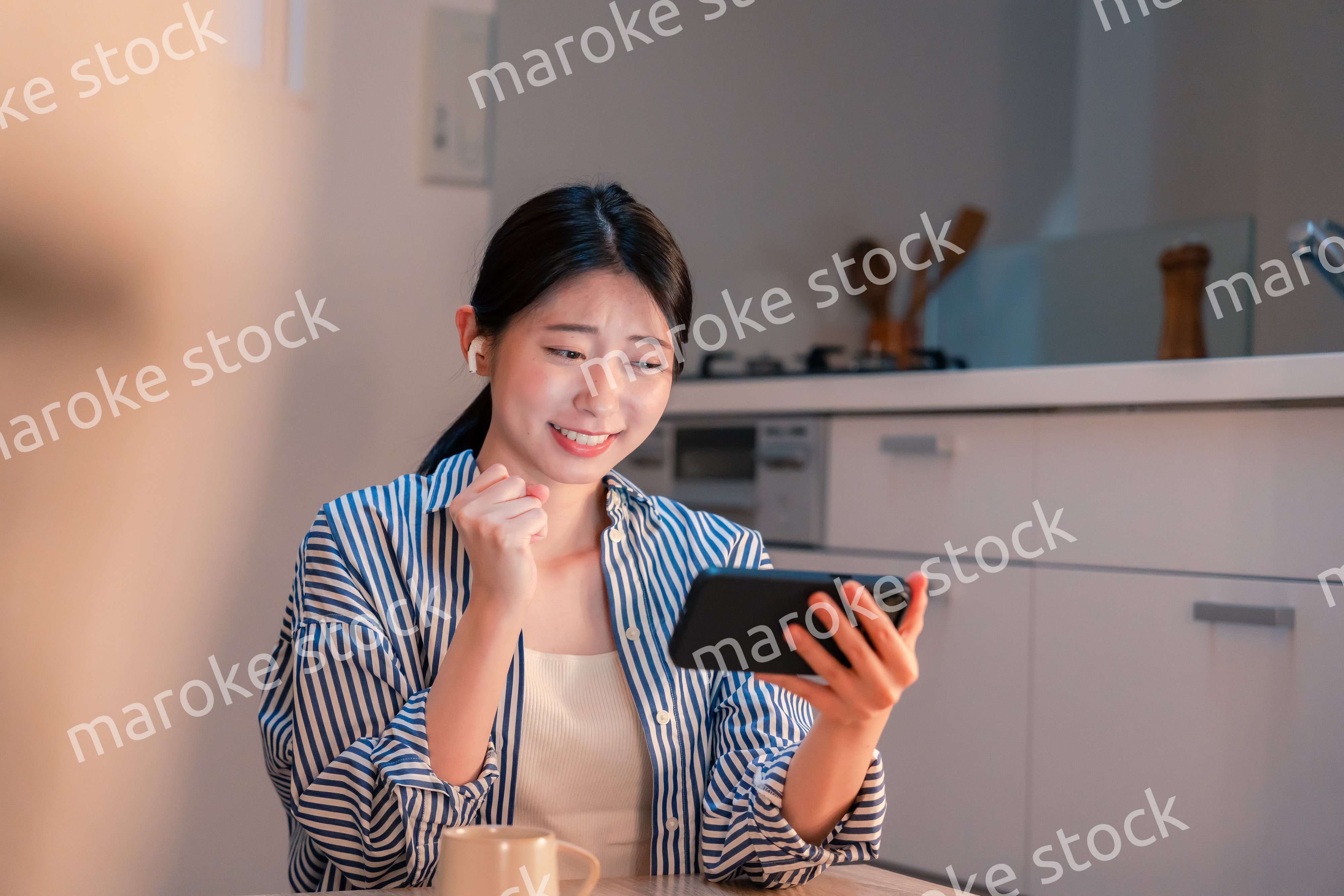 夜に家でスマホでスポーツ観戦をする若い女性