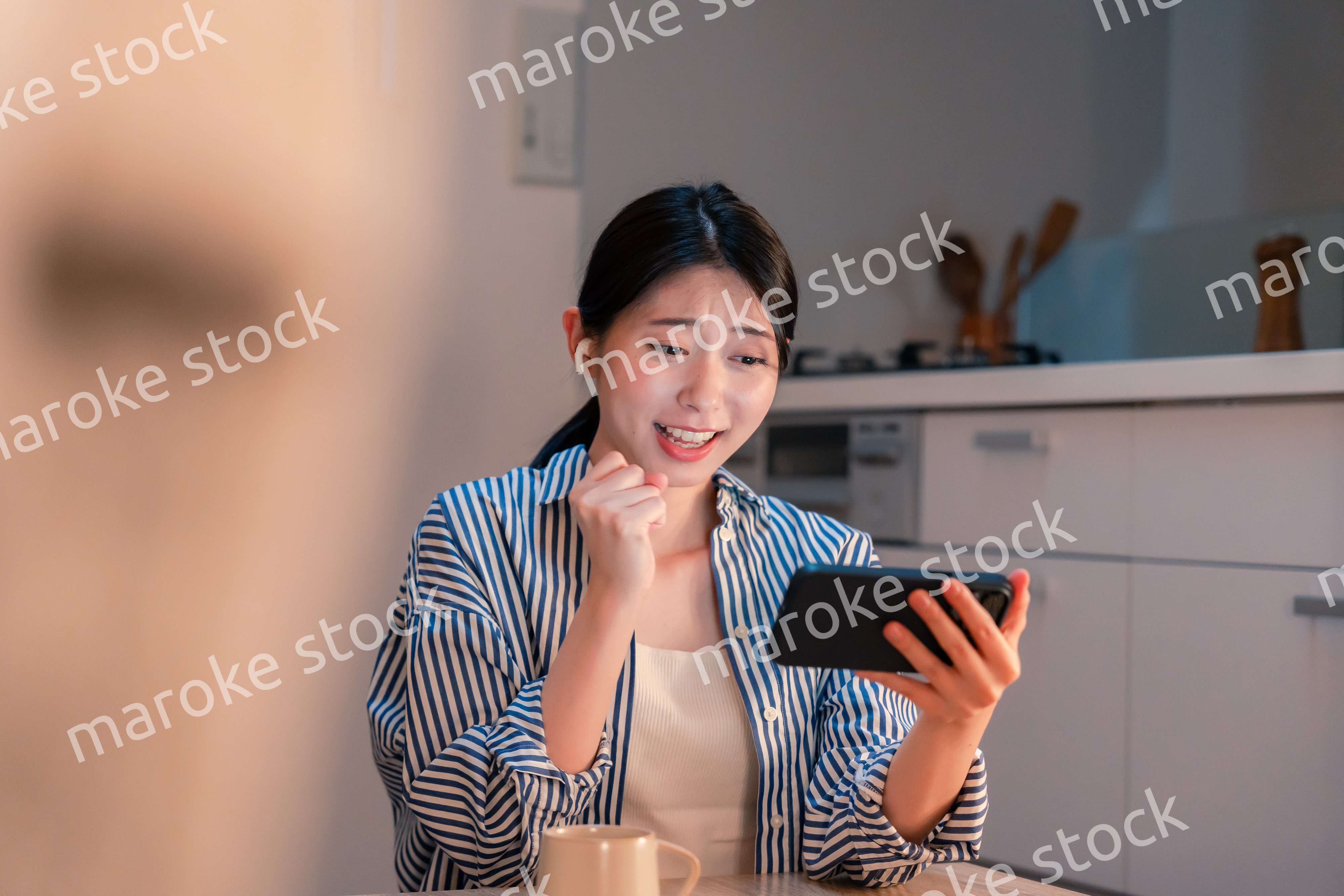 夜に家でスマホでスポーツ観戦をする若い女性