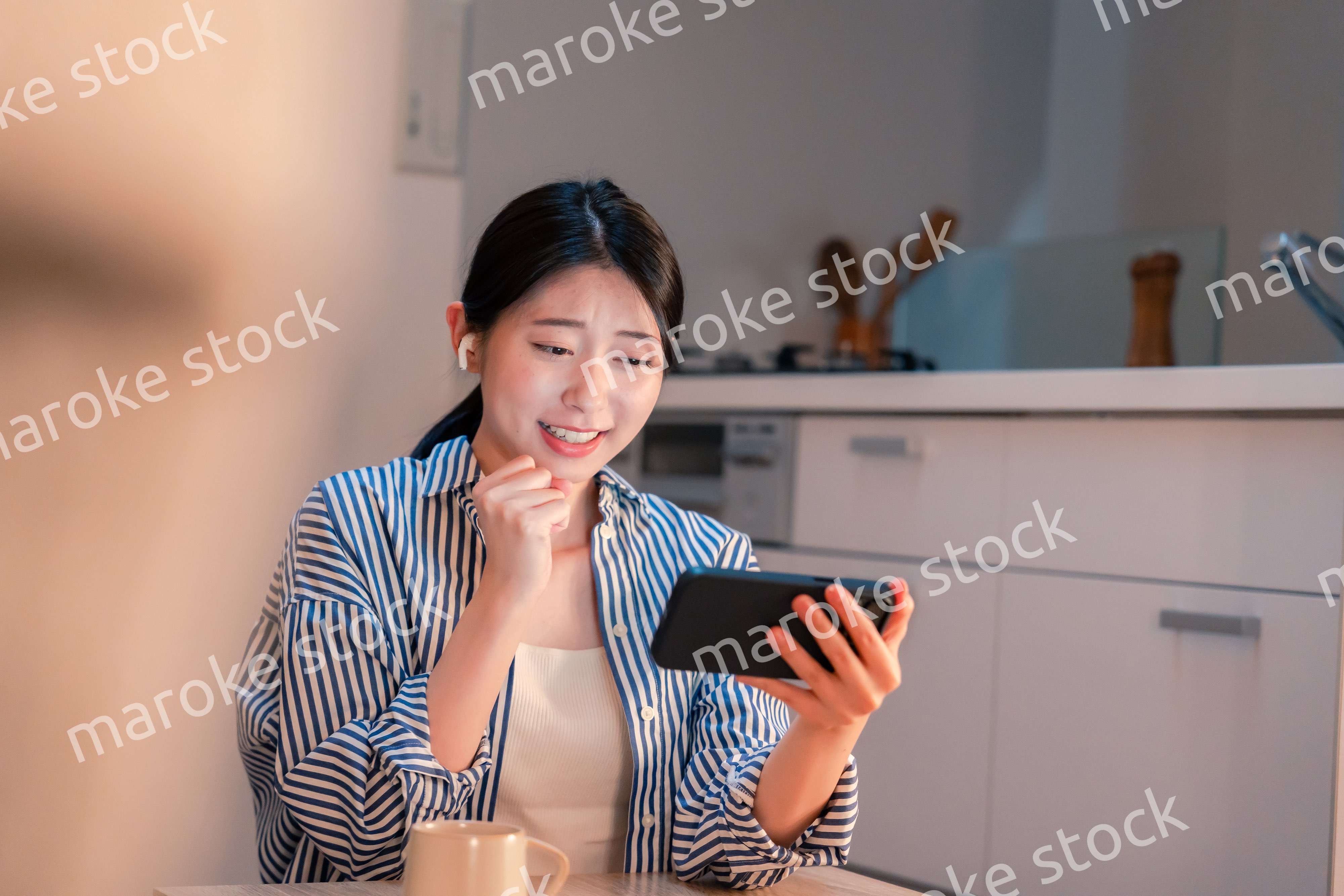 夜に家でスマホでスポーツ観戦をする若い女性