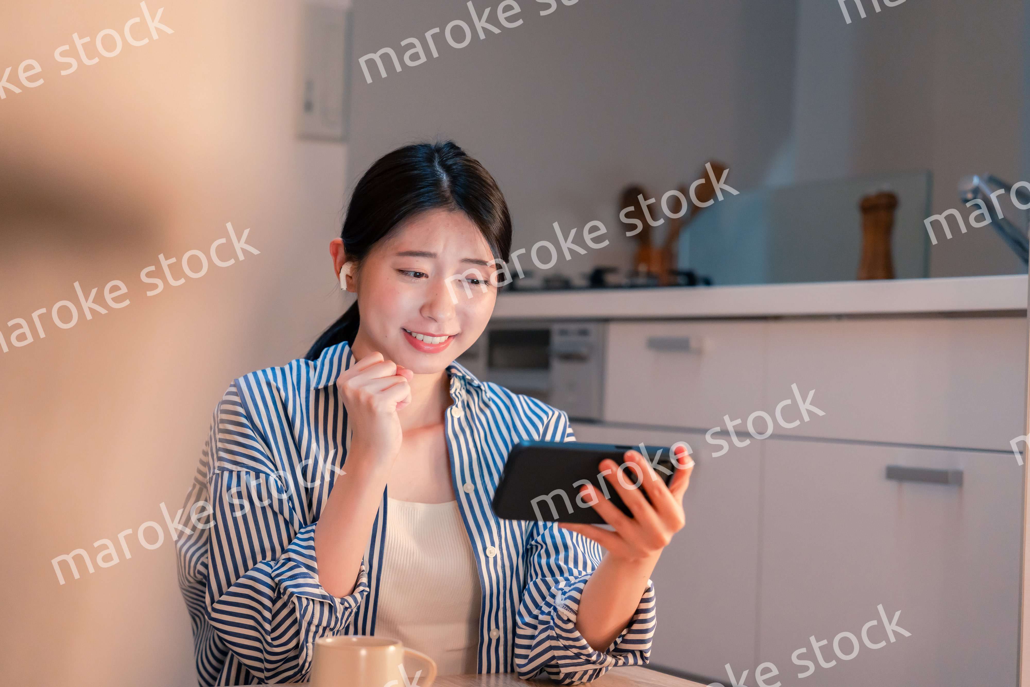 夜に家でスマホでスポーツ観戦をする若い女性