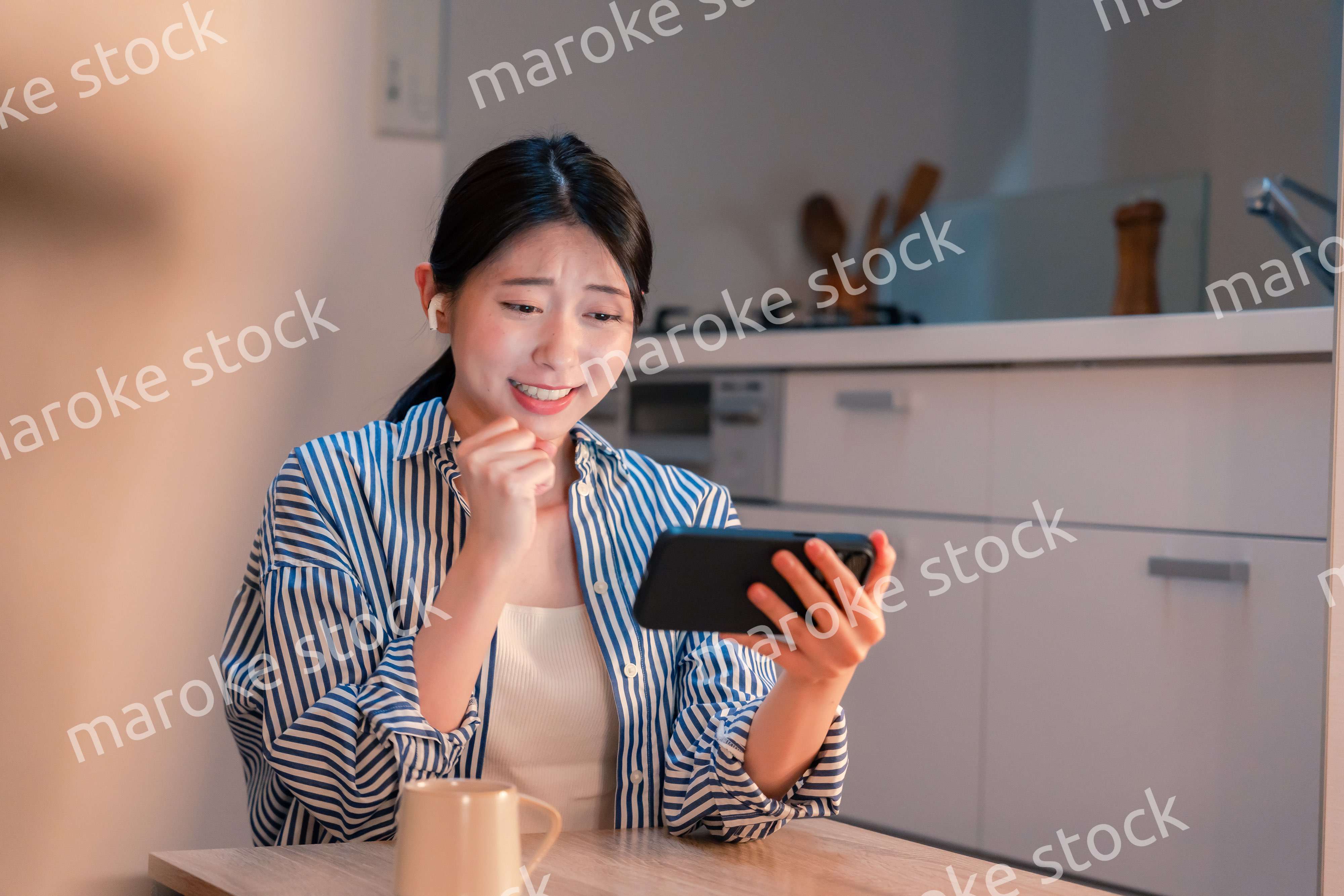 夜に家でスマホでスポーツ観戦をする若い女性