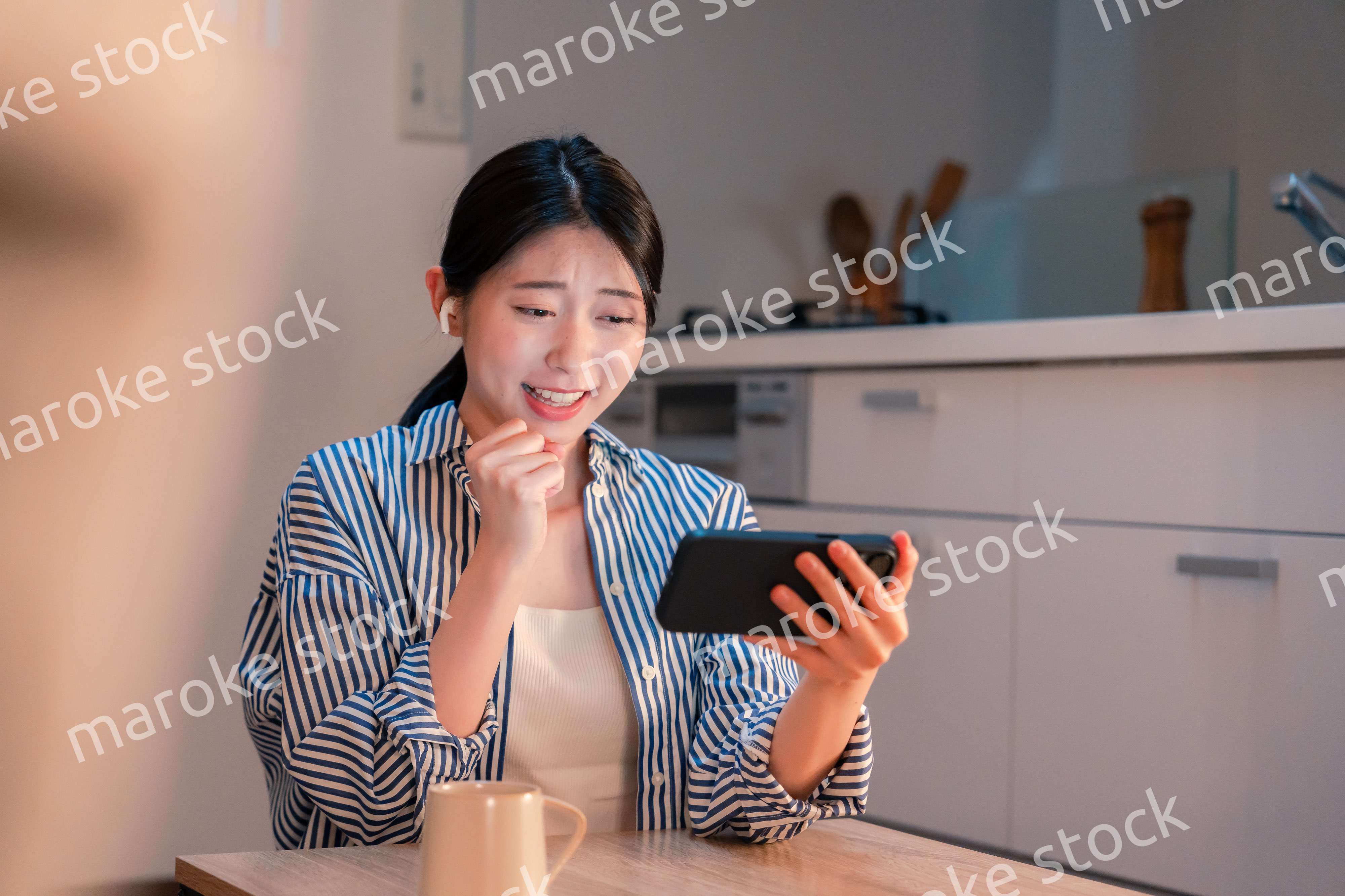 夜に家でスマホでスポーツ観戦をする若い女性