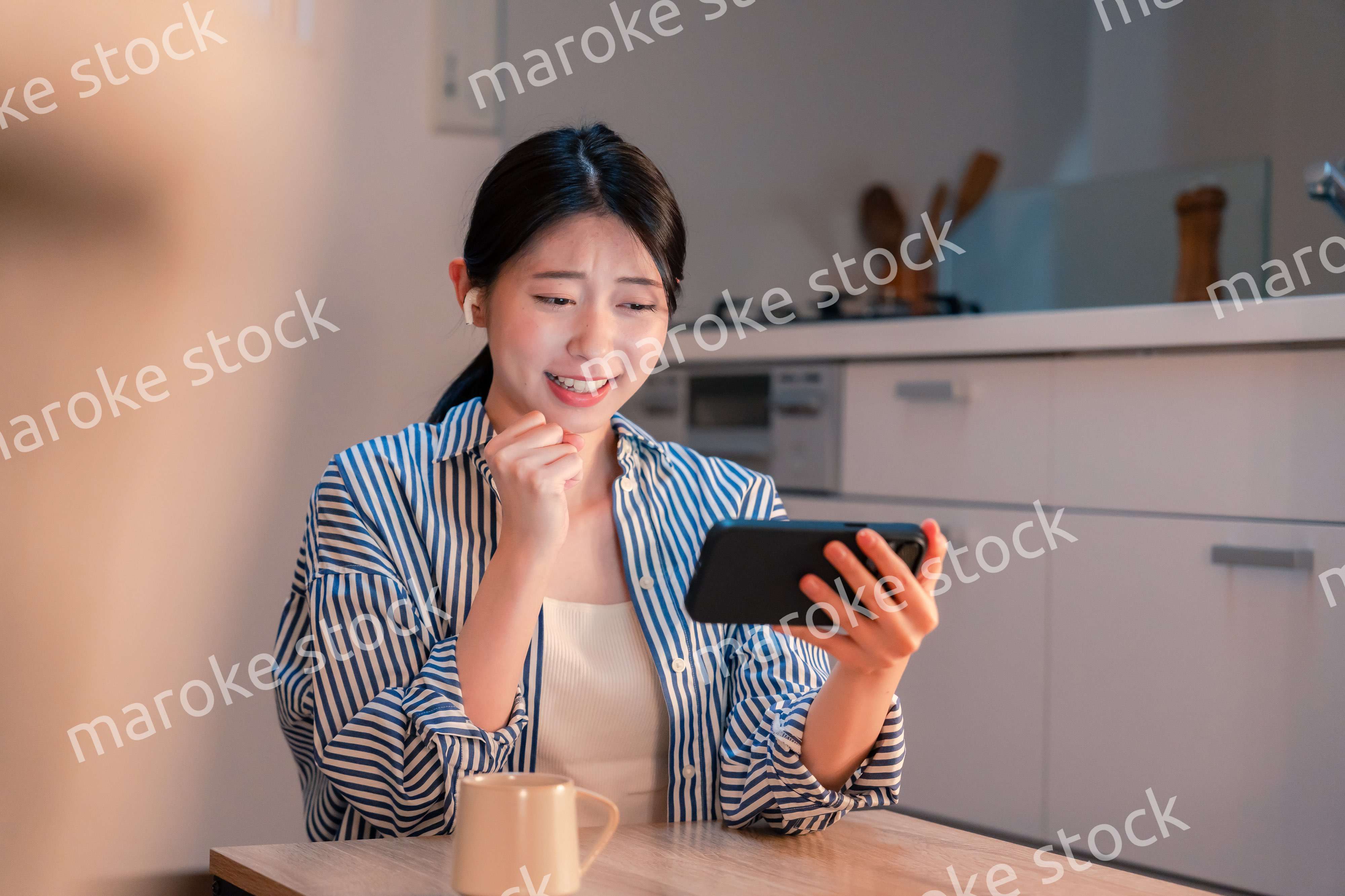 夜に家でスマホでスポーツ観戦をする若い女性