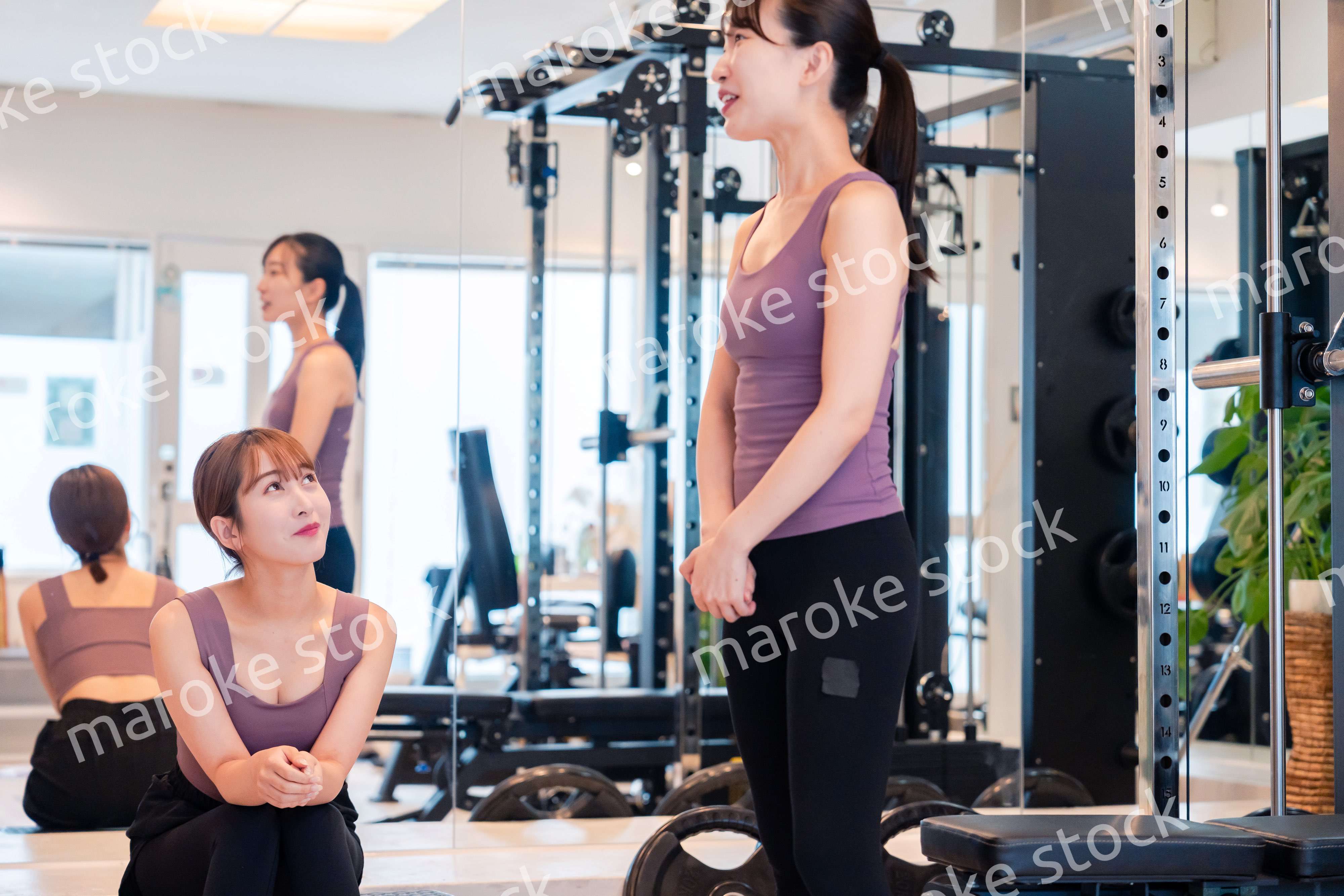 ジムで運動をしながら楽しく話をする女性