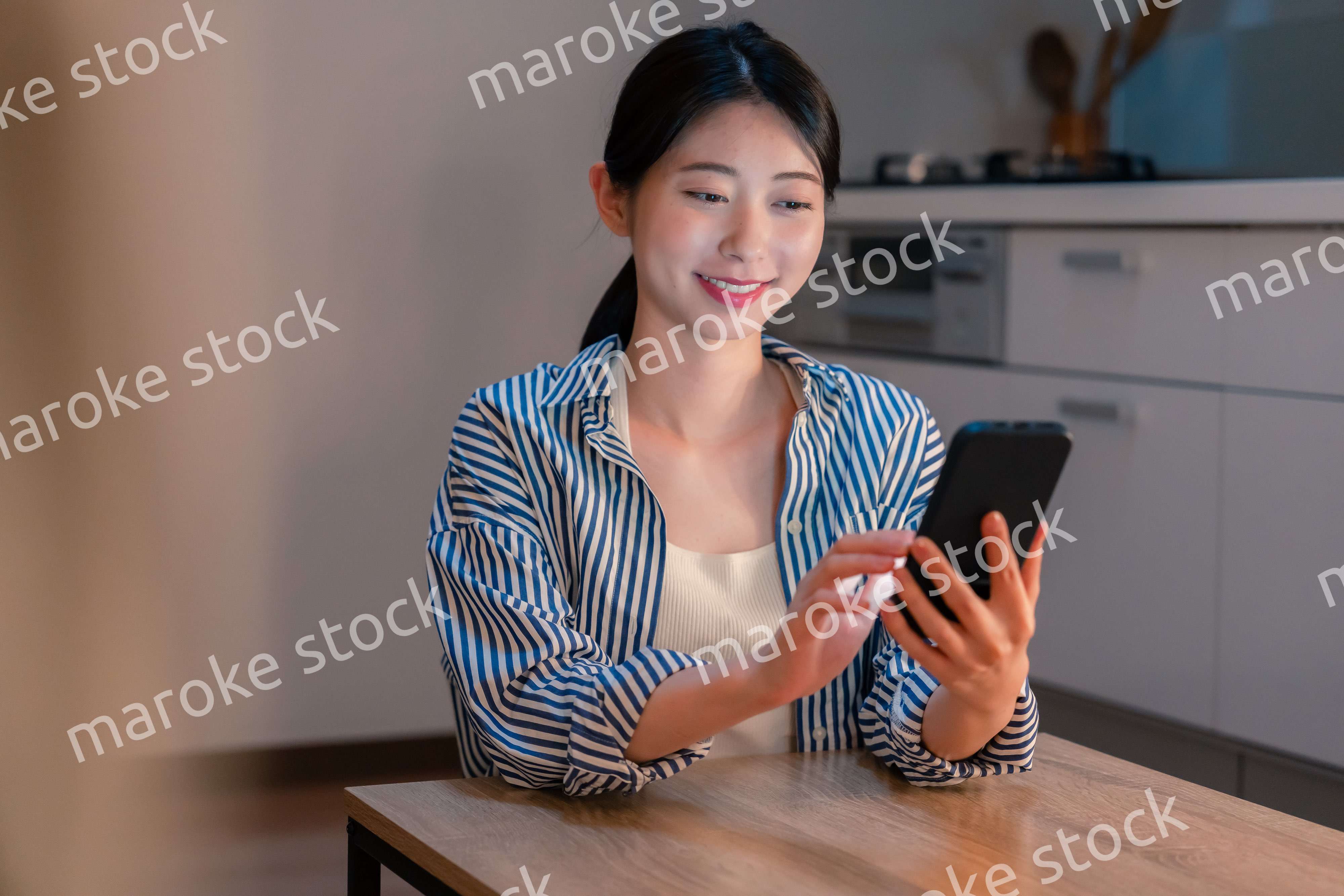 夜遅くに笑顔でスマホを使う若い女性