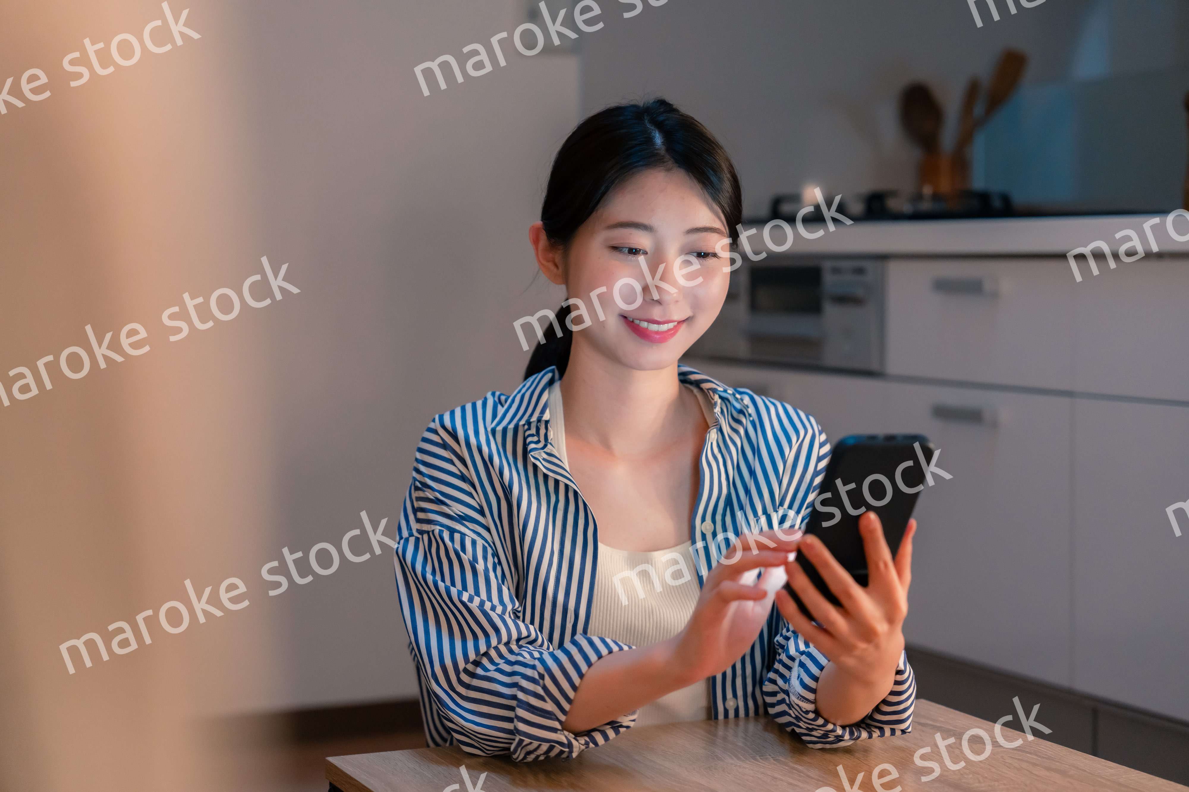 夜遅くに笑顔でスマホを使う若い女性