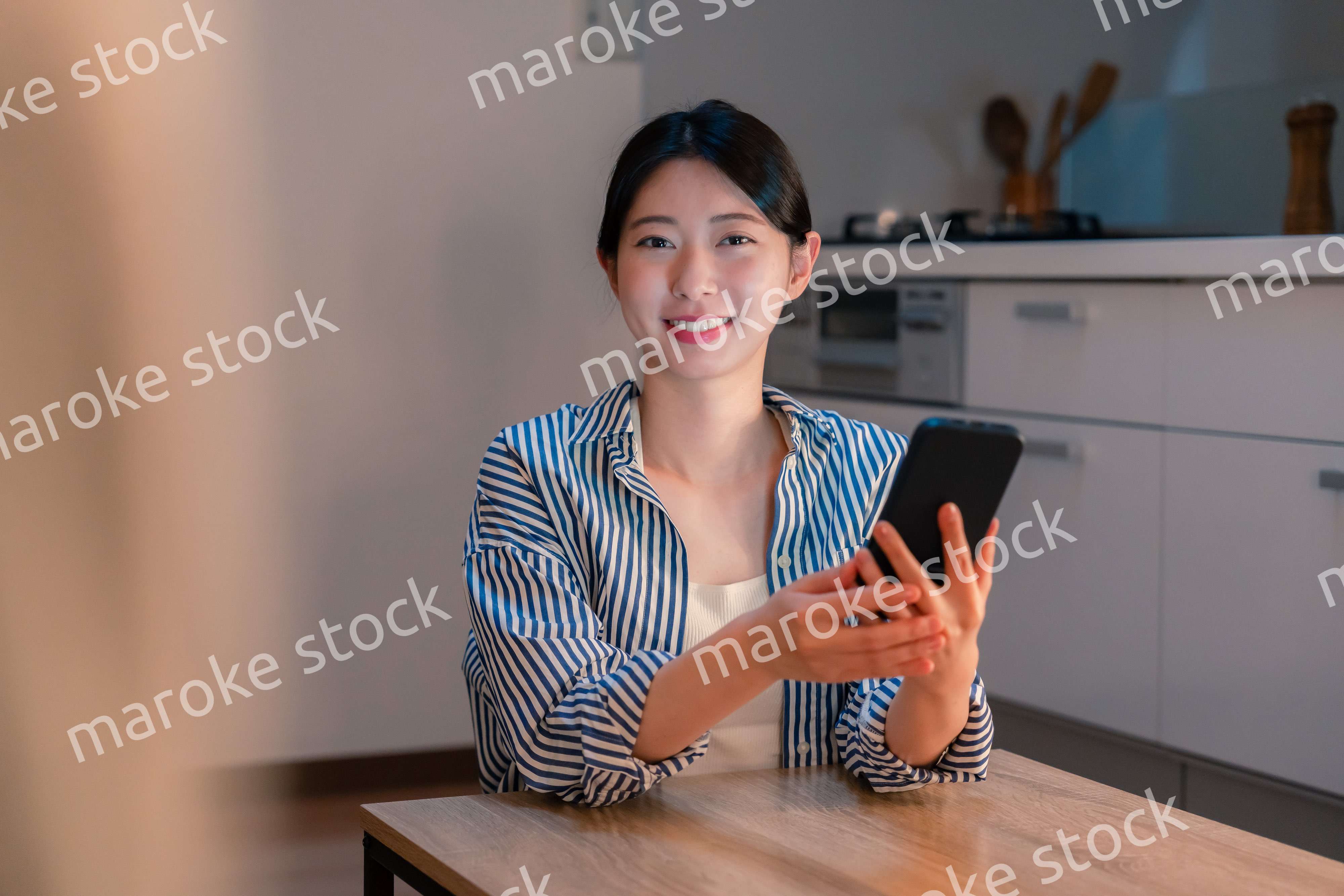 夜遅くに笑顔でスマホを使う若い女性