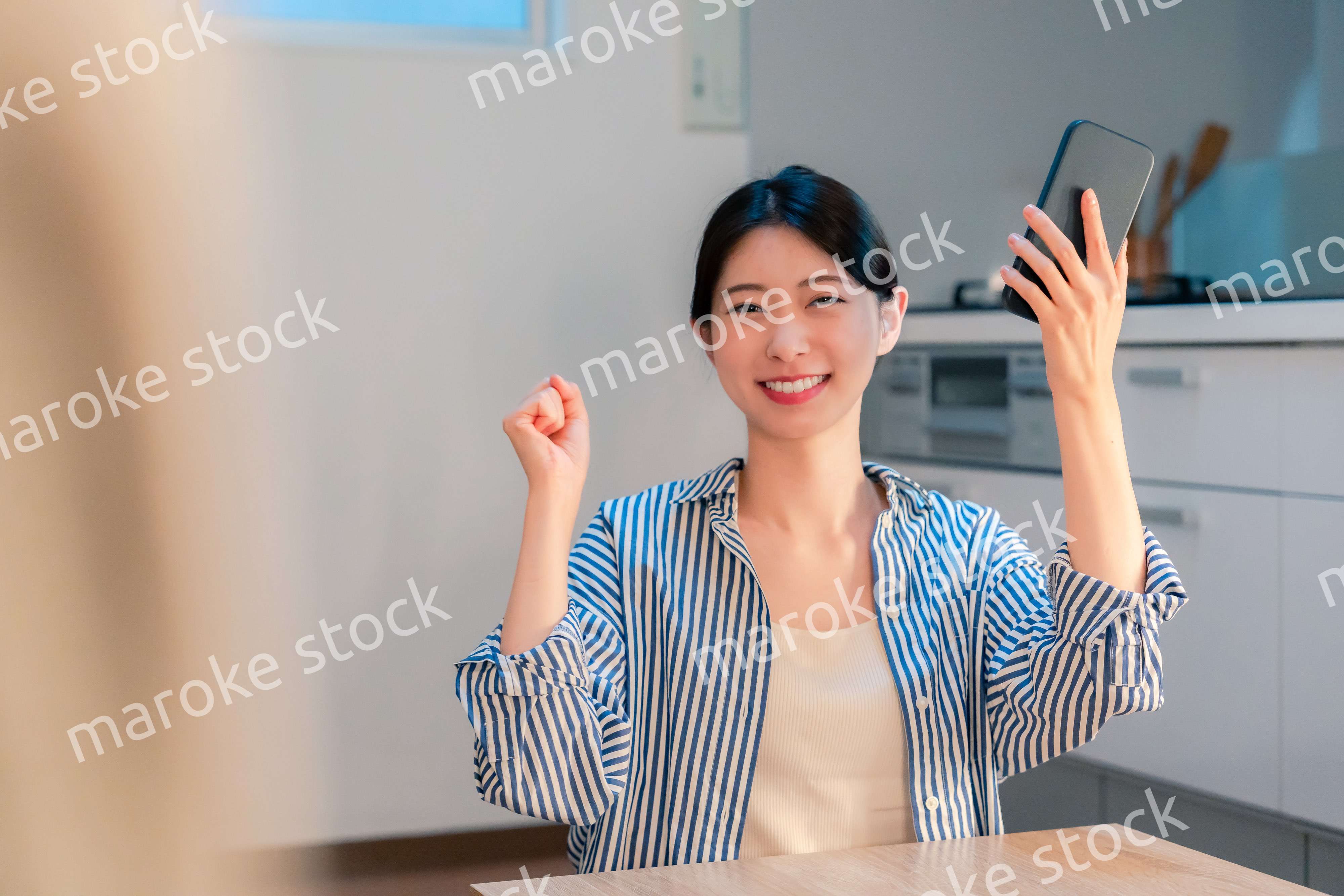 家で夜にスマホを持って大喜びをする若い女性