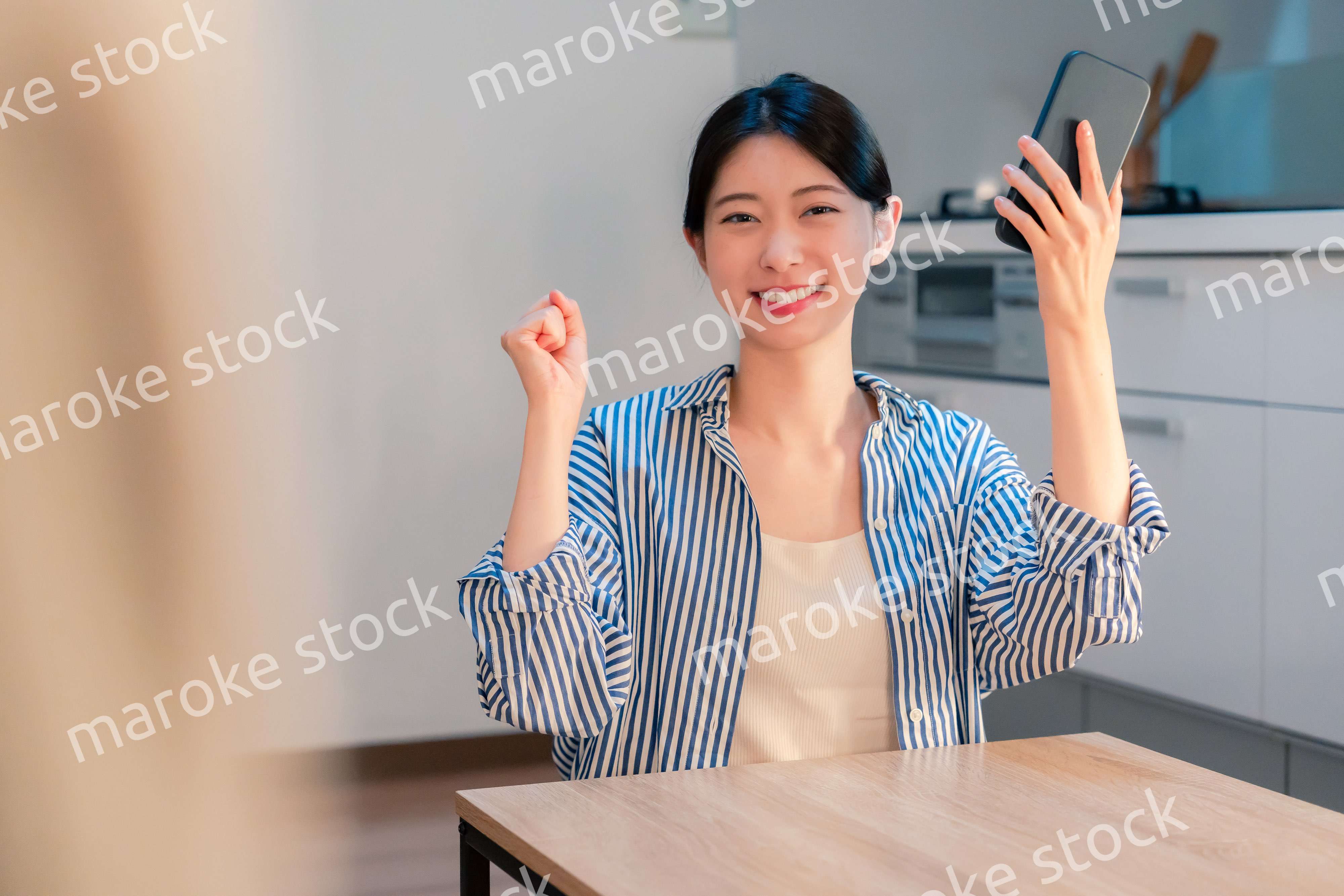 家で夜にスマホを持って大喜びをする若い女性