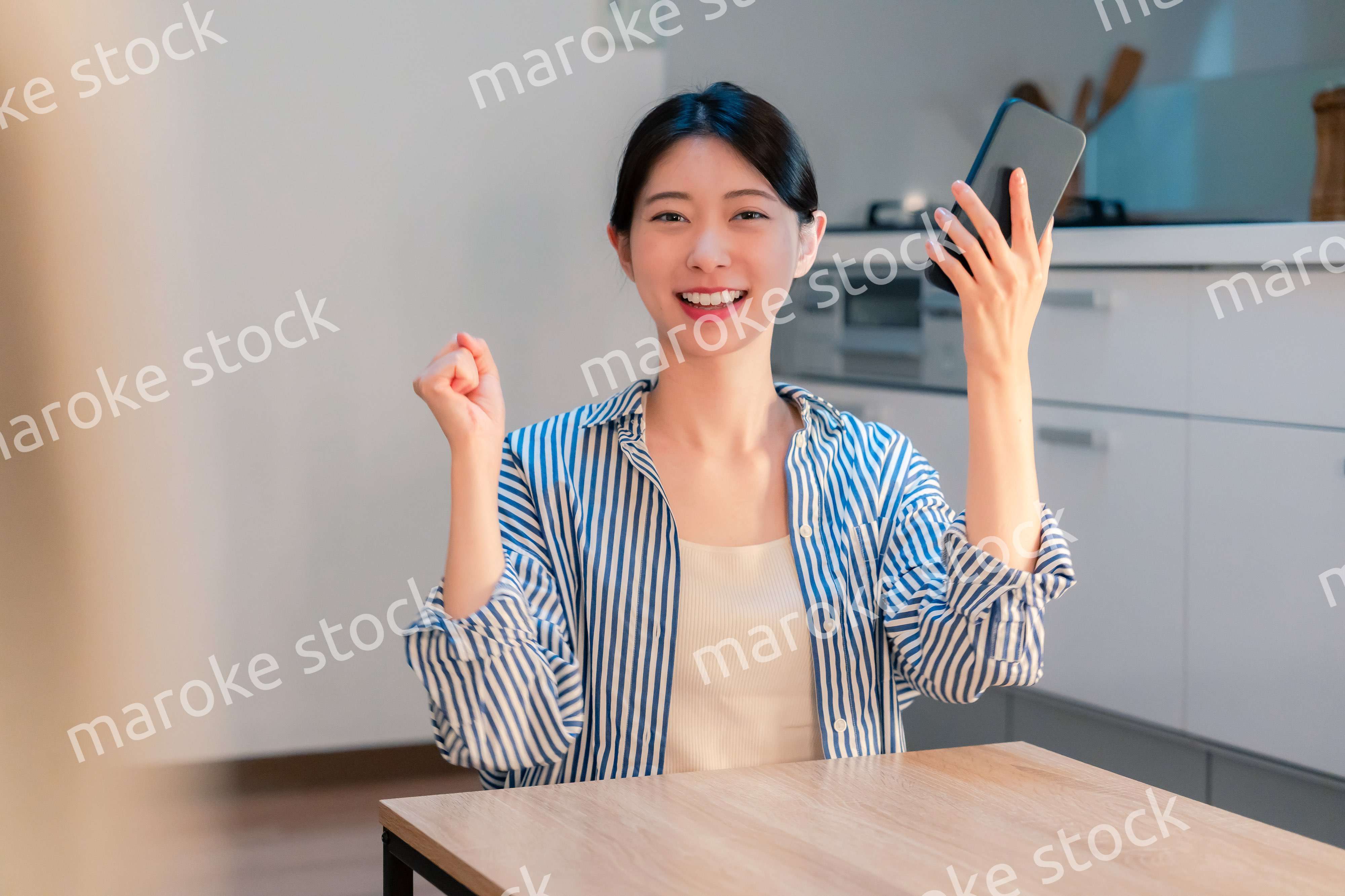 家で夜にスマホを持って大喜びをする若い女性