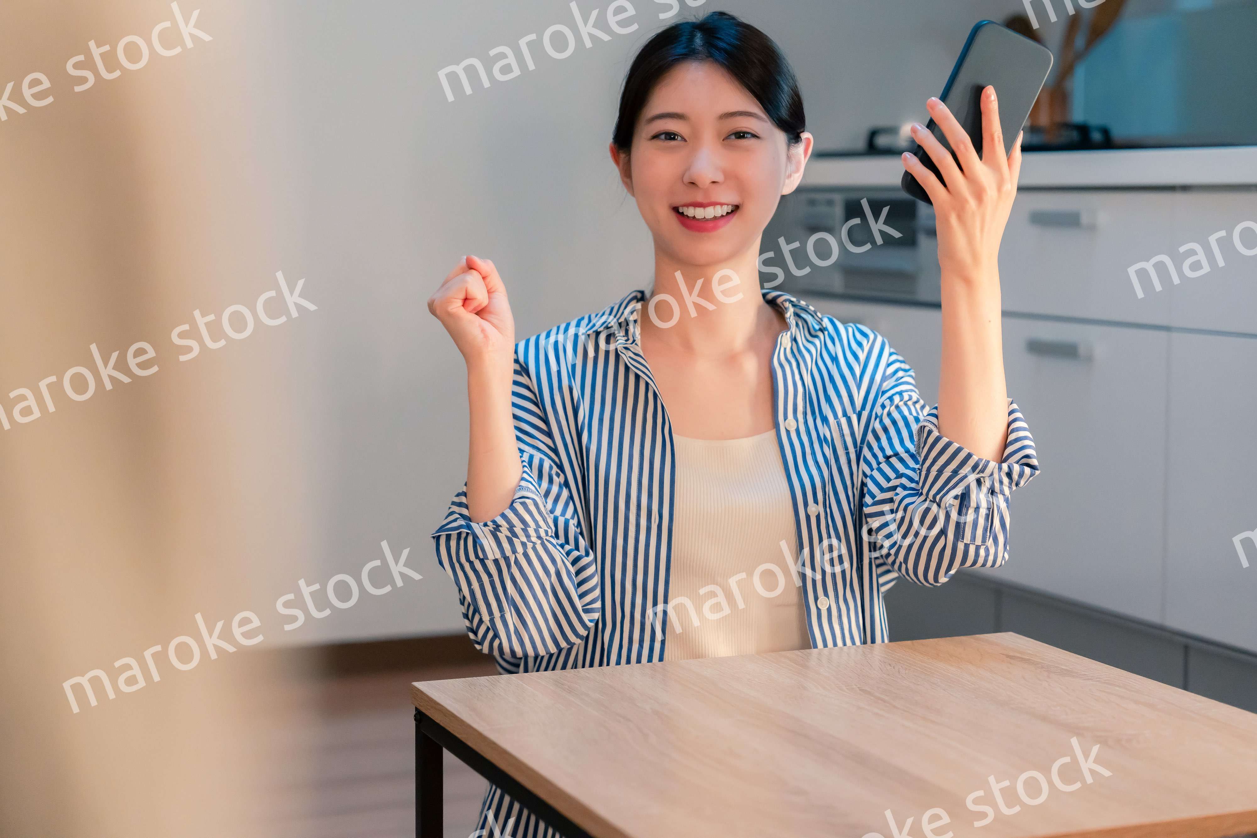 家で夜にスマホを持って大喜びをする若い女性