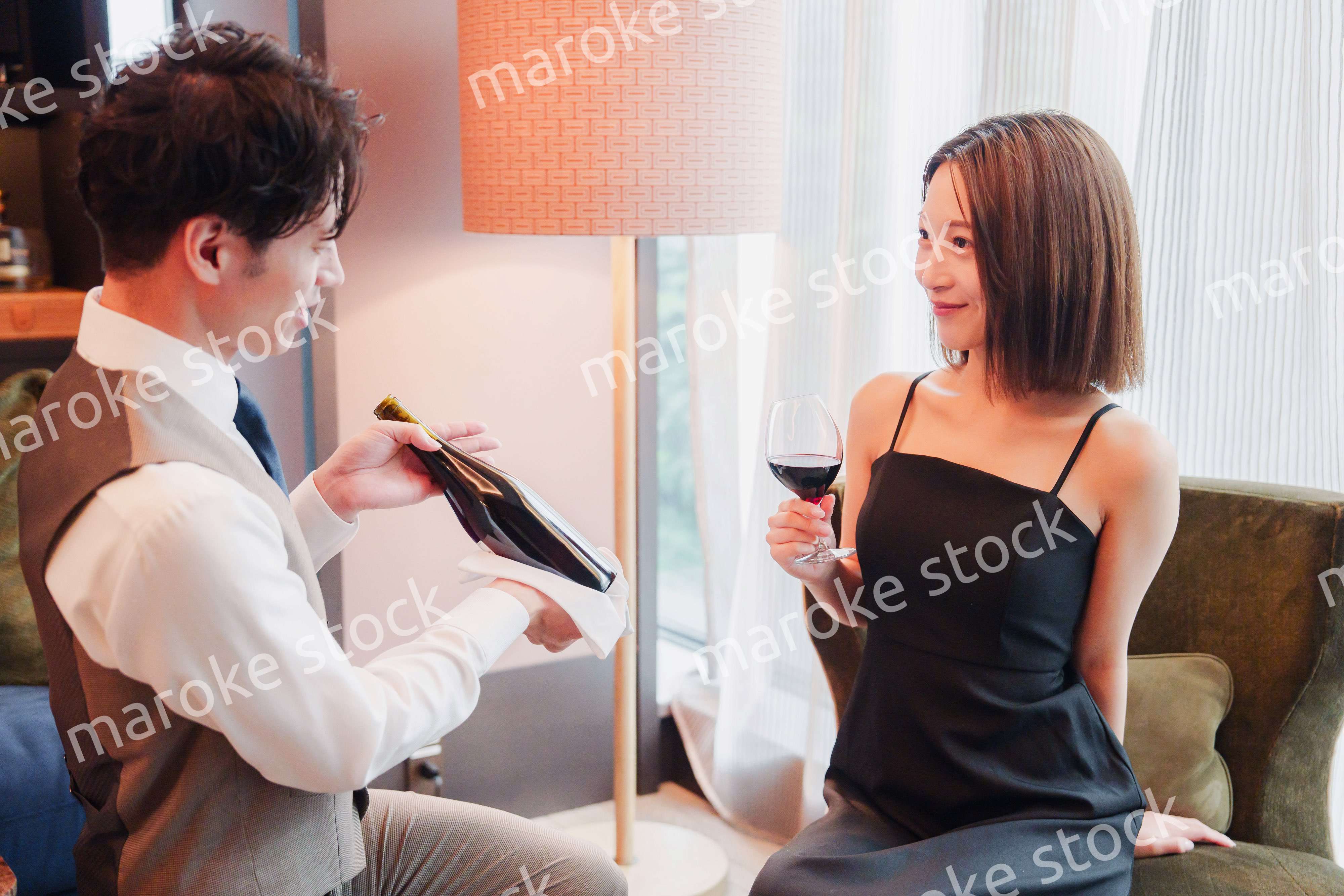 ホテルのルームサービスで女性にワインを提供する男性スタッフ