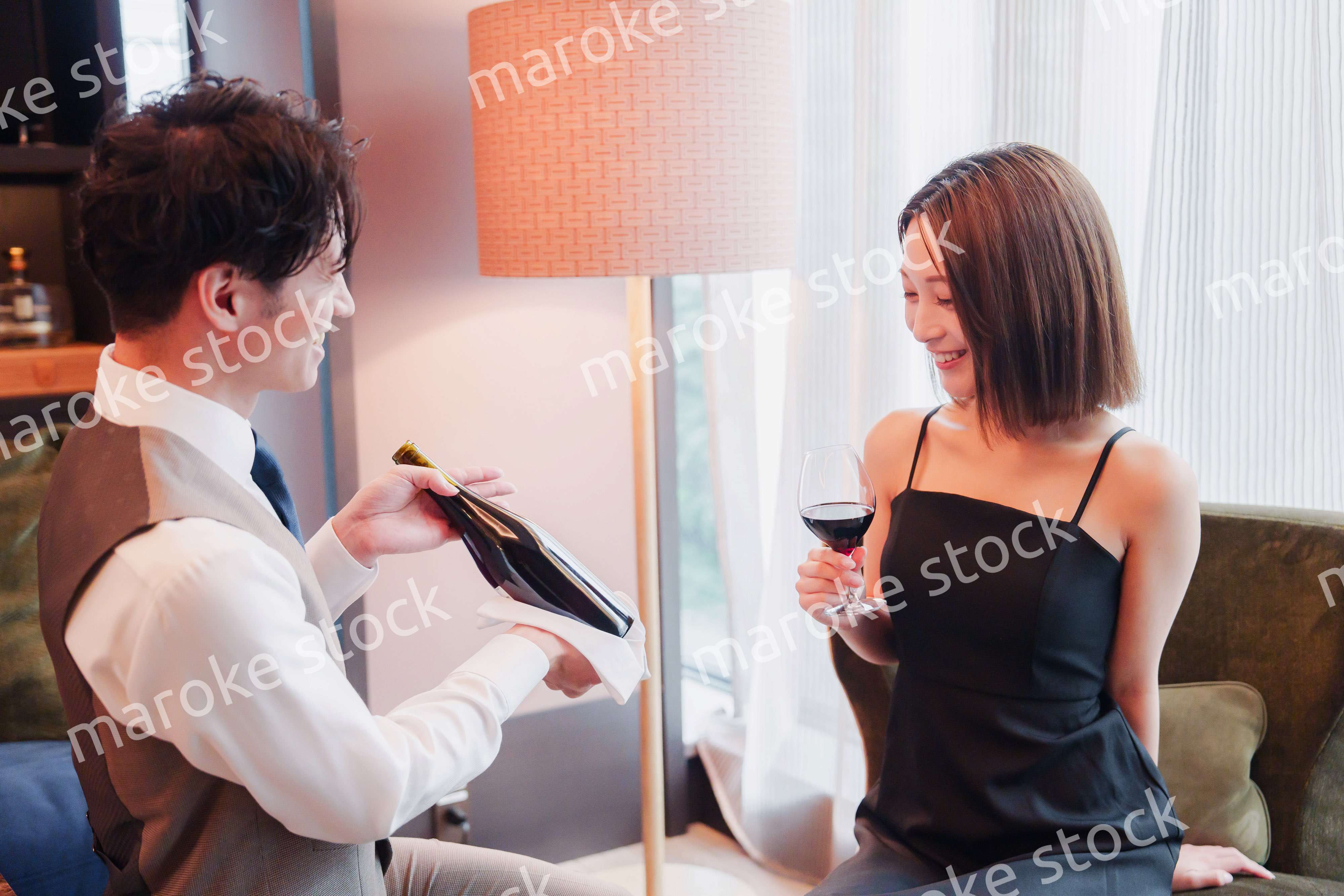 ホテルのルームサービスで女性にワインを提供する男性スタッフ