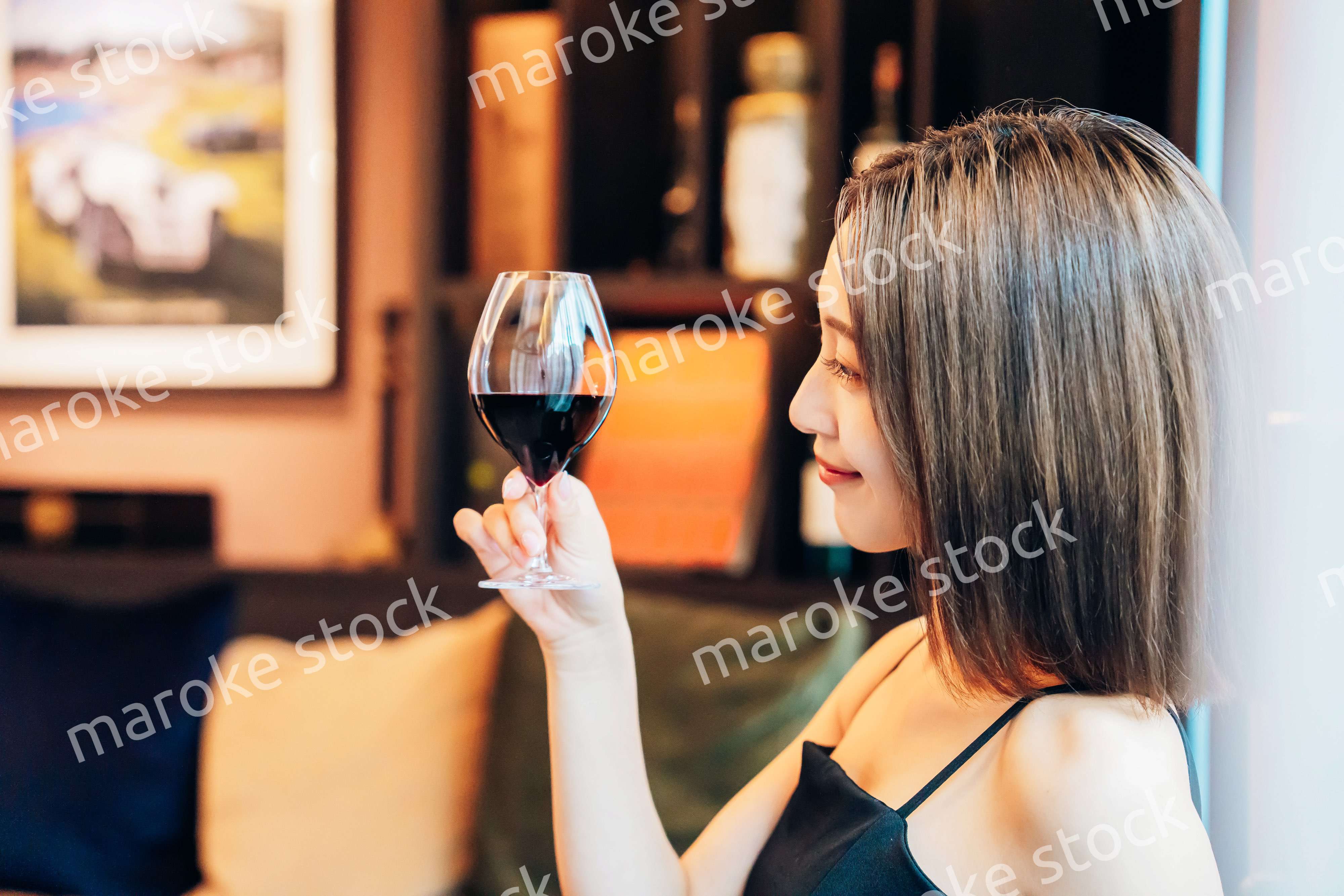 ラグジュアリーな雰囲気のお店で赤ワインを飲む若い女性